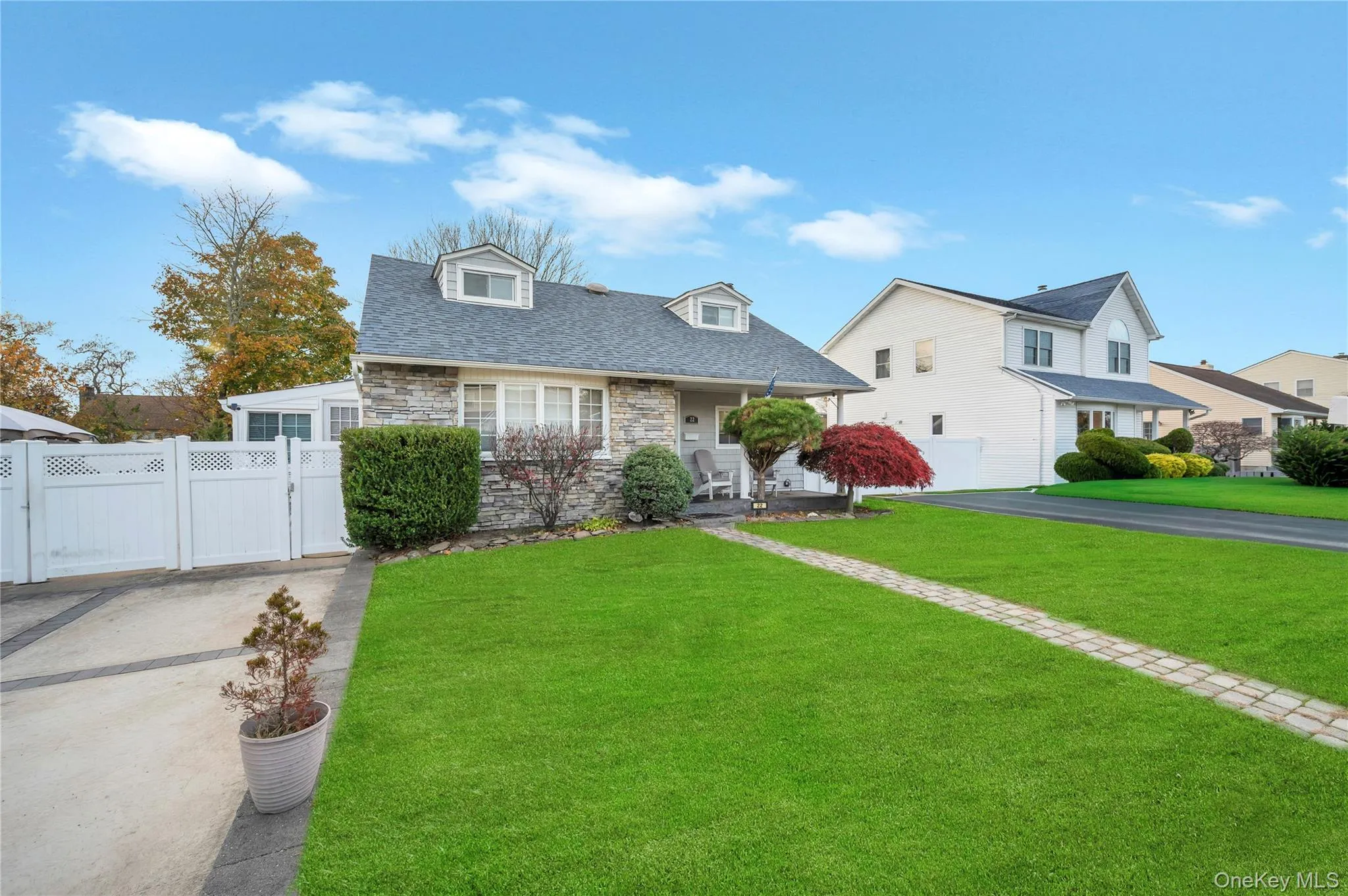Cape cod house with stone siding, covered porch, a gate, and roof with shingles Cape cod house with stone siding, covered porch, a gate, and roof with shingles