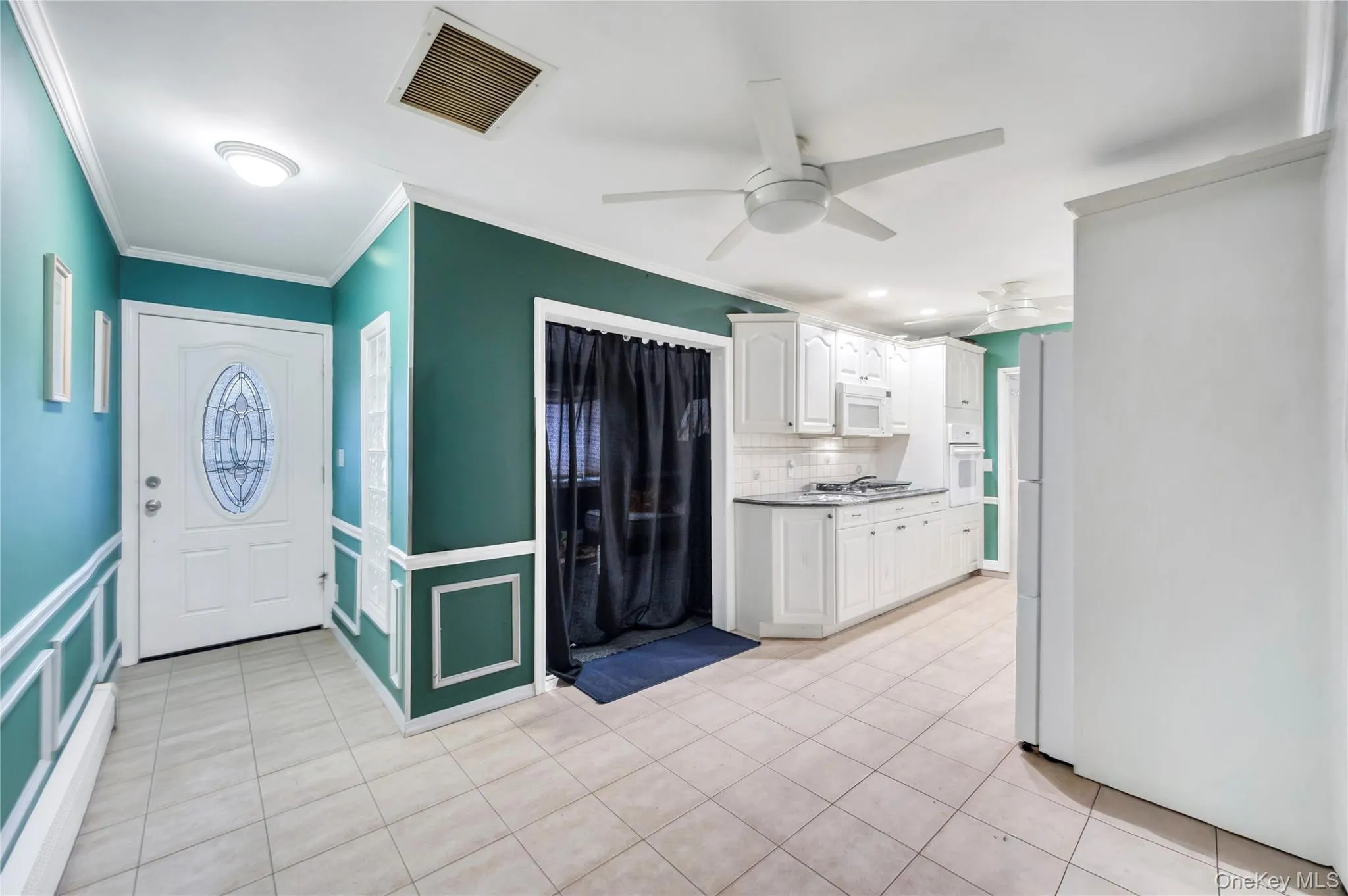 Kitchen with white cabinets, tasteful backsplash, ceiling fan, light tile patterned floors, and ornamental molding Kitchen with white cabinets, tasteful backsplash, ceiling fan, light tile patterned floors, and ornamental molding
