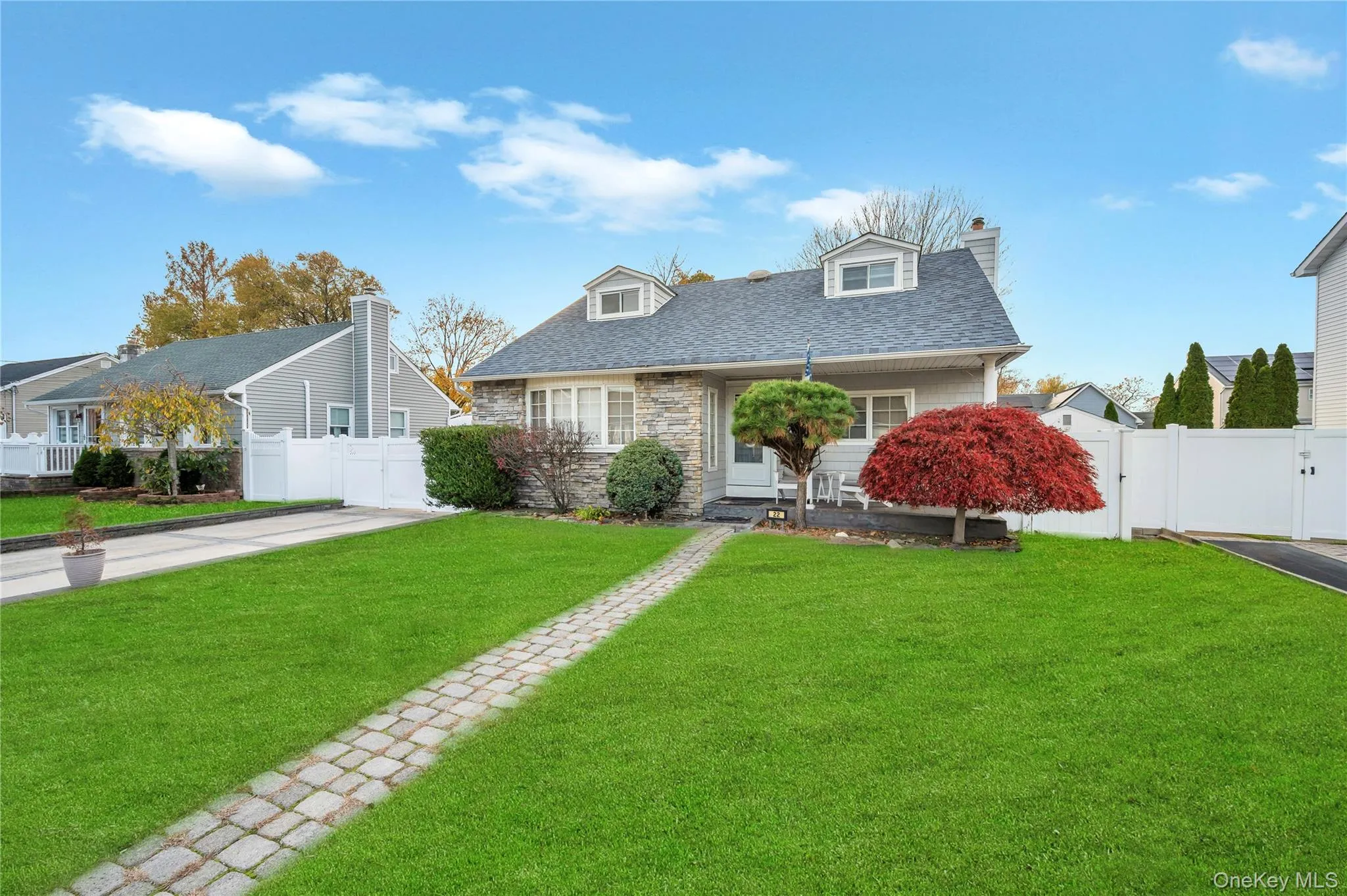 Cape cod-style house featuring a chimney, a gate, stone siding, and roof with shingles Cape cod-style house featuring a chimney, a gate, stone siding, and roof with shingles