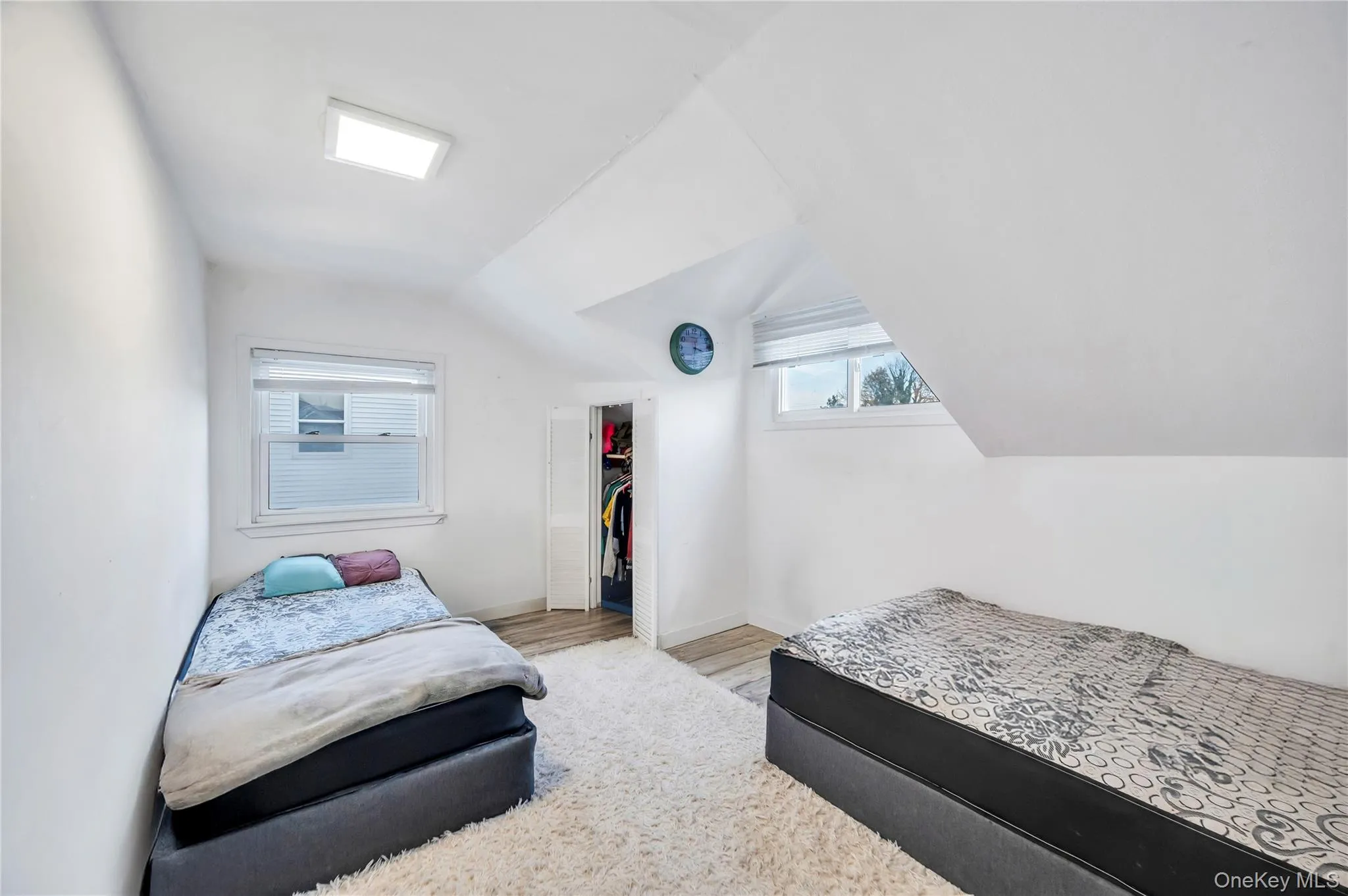 Bedroom with vaulted ceiling, wood finished floors, and a spacious closet Bedroom with vaulted ceiling, wood finished floors, and a spacious closet
