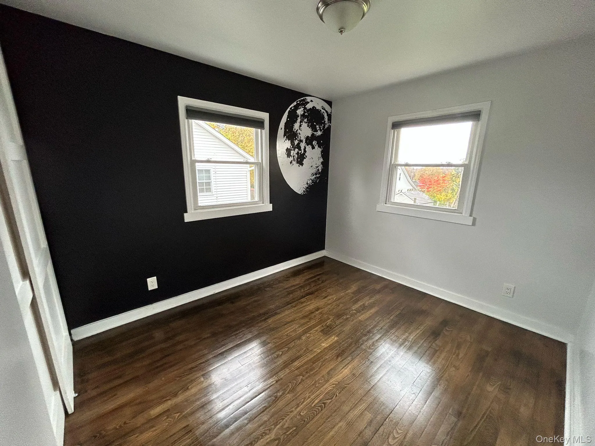Spare room featuring dark wood-style flooring and plenty of natural light Spare room featuring dark wood-style flooring and plenty of natural light