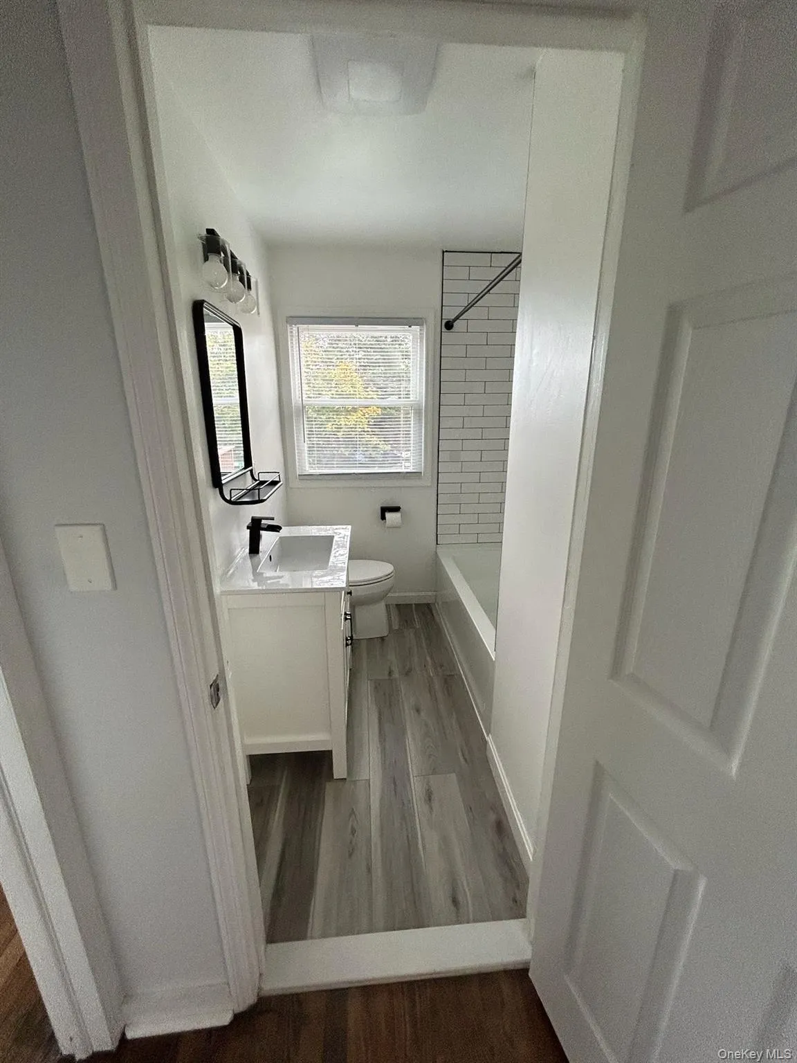 Bathroom featuring vanity, dark wood-style floors, and shower / bath combination Bathroom featuring vanity, dark wood-style floors, and shower / bath combination