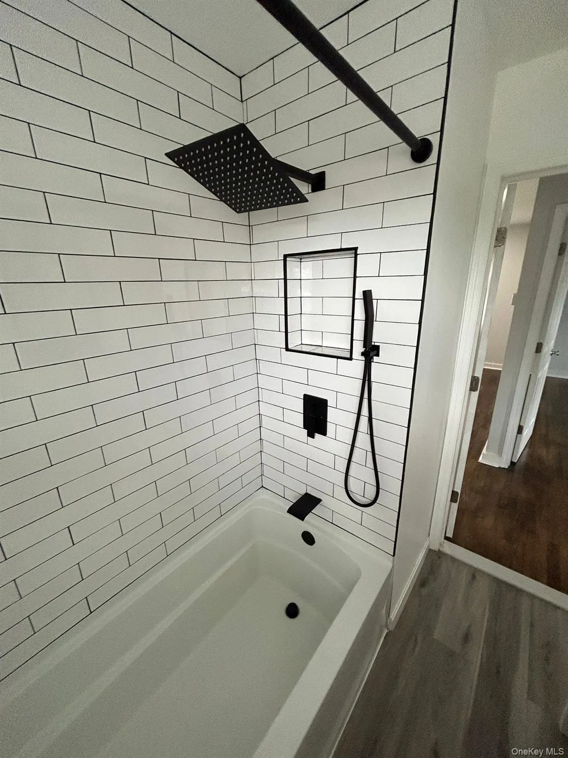 Full bathroom featuring dark wood finished floors and tiled shower / bath Full bathroom featuring dark wood finished floors and tiled shower / bath