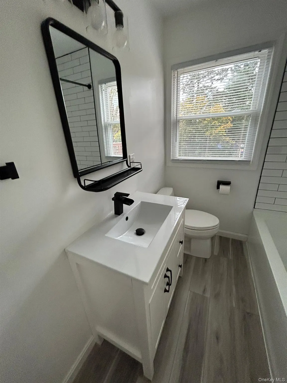 Bathroom featuring dark wood-style flooring, vanity, and healthy amount of natural light Bathroom featuring dark wood-style flooring, vanity, and healthy amount of natural light