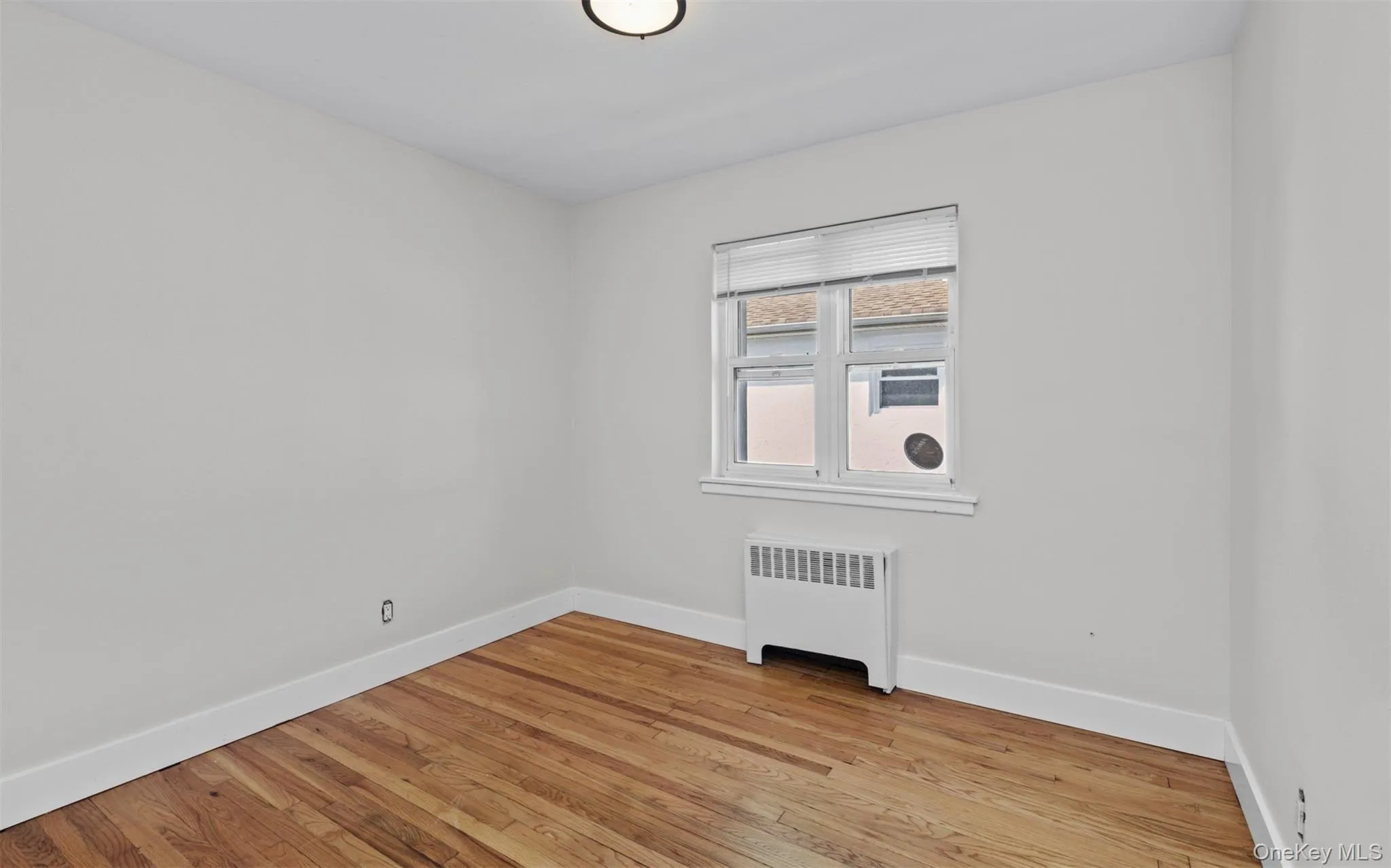 Unfurnished room with radiator heating unit and light wood-type flooring Unfurnished room with radiator heating unit and light wood-type flooring