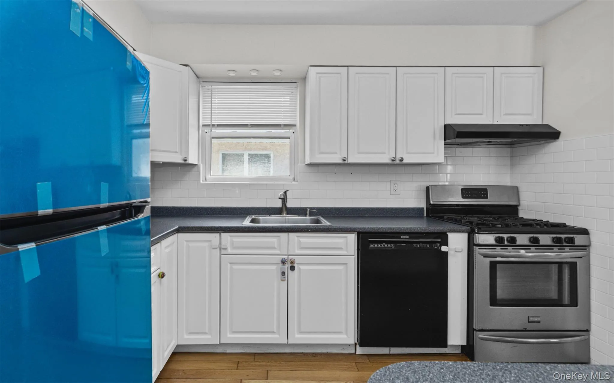 Kitchen featuring appliances with stainless steel finishes, white cabinetry, and dark countertops Kitchen featuring appliances with stainless steel finishes, white cabinetry, and dark countertops