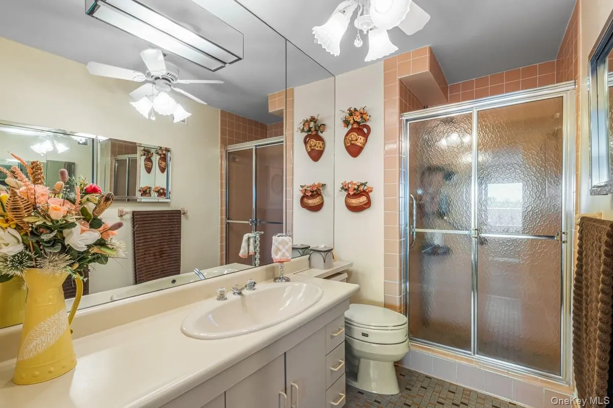 Full bathroom with a ceiling fan, a shower stall, vanity, and tile patterned floors Full bathroom with a ceiling fan, a shower stall, vanity, and tile patterned floors