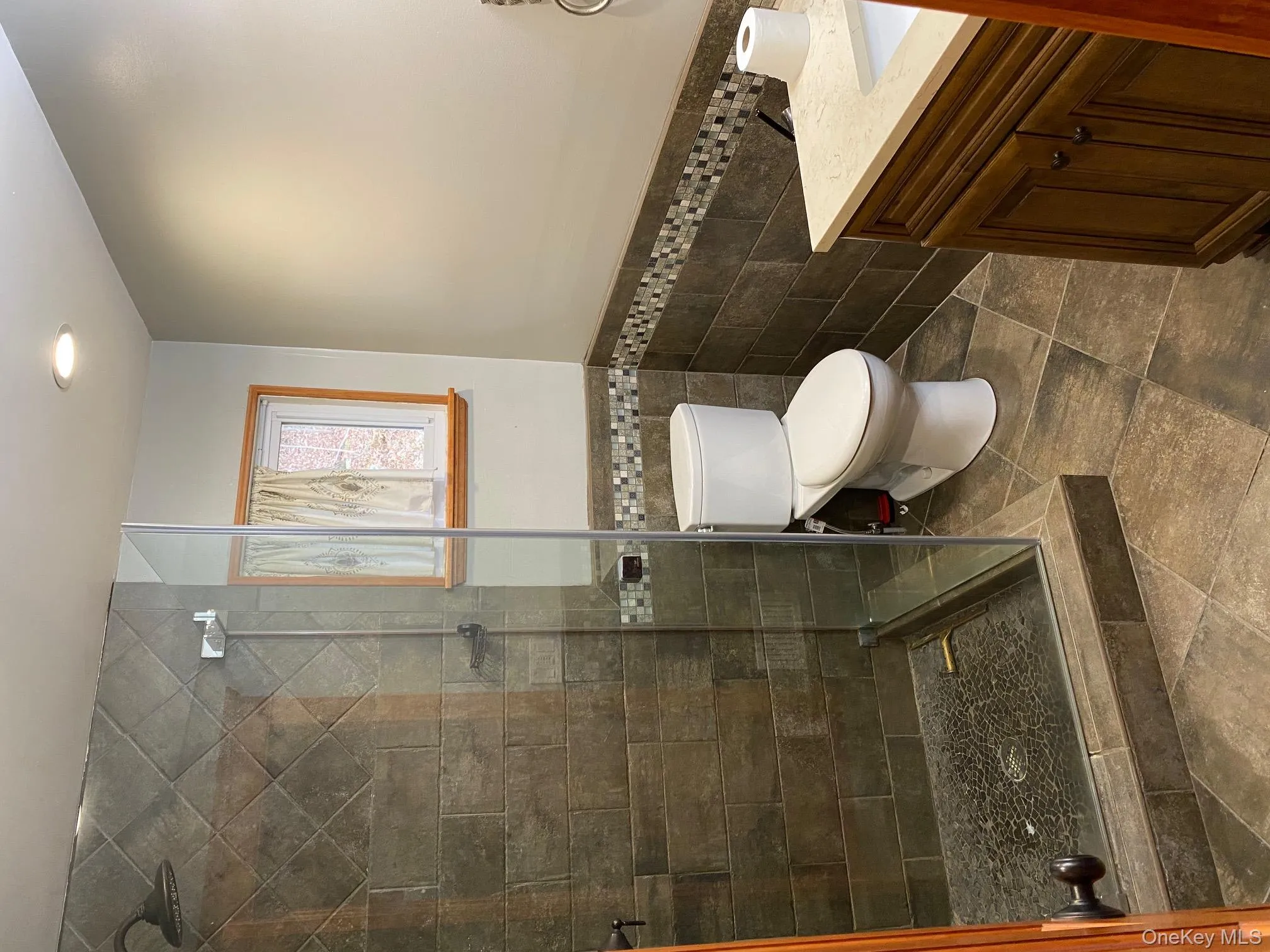 Bathroom featuring vanity, a shower stall, wainscoting, tile walls, and recessed lighting Bathroom featuring vanity, a shower stall, wainscoting, tile walls, and recessed lighting