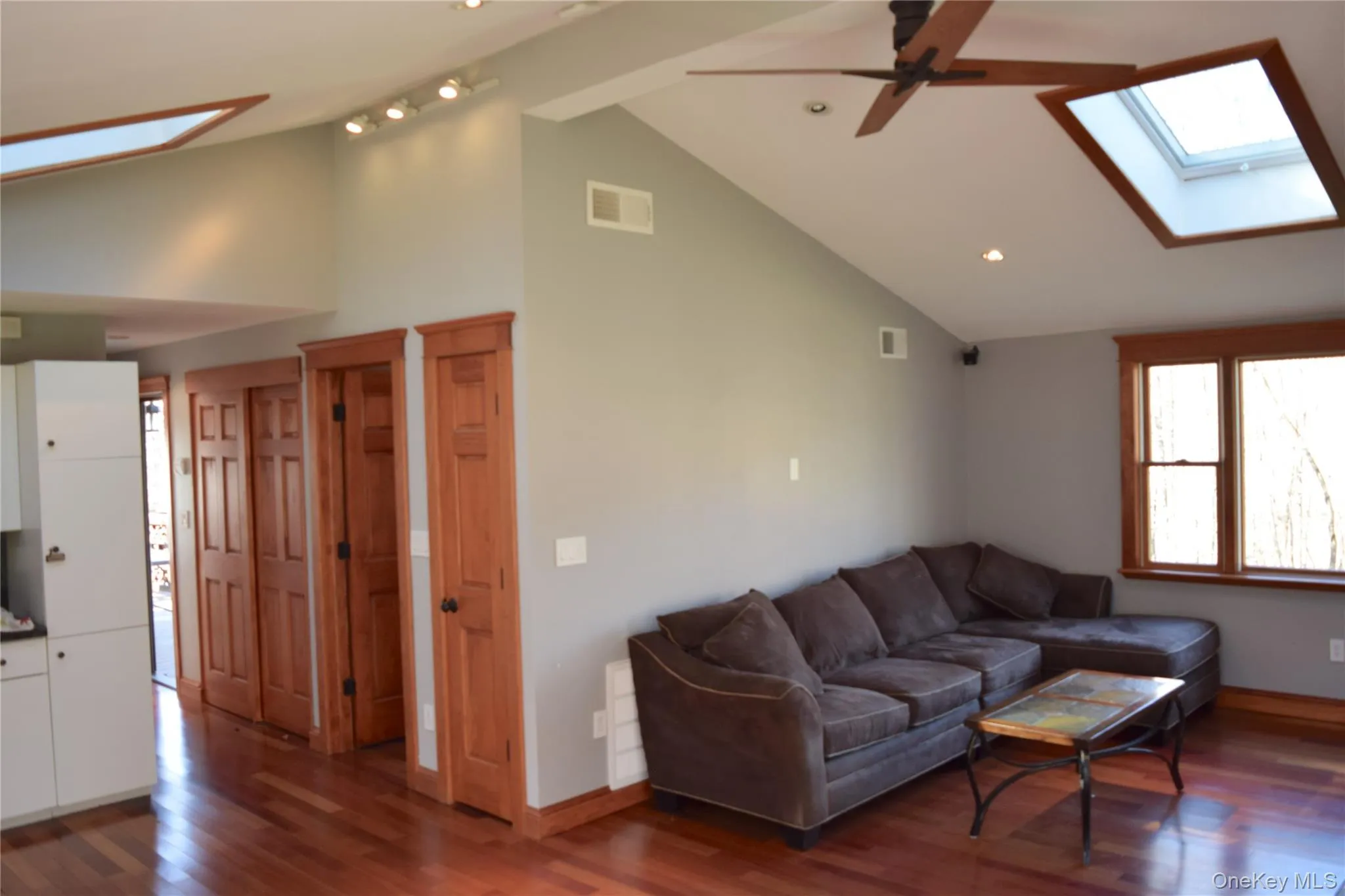 Living room featuring a skylight, dark wood-type flooring, ceiling fan, recessed lighting, and high vaulted ceiling Living room featuring a skylight, dark wood-type flooring, ceiling fan, recessed lighting, and high vaulted ceiling