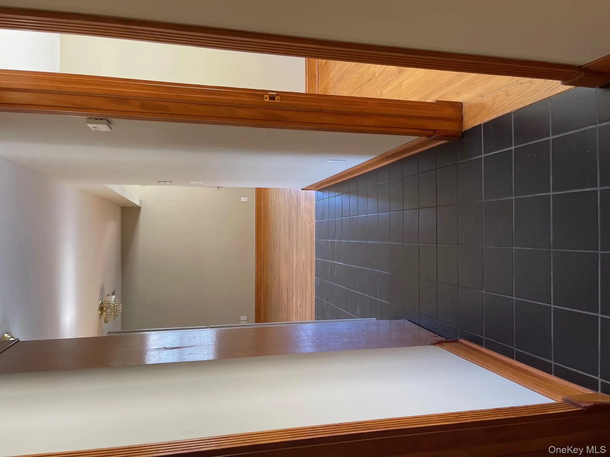Corridor featuring dark tile patterned flooring and baseboards Corridor featuring dark tile patterned flooring and baseboards
