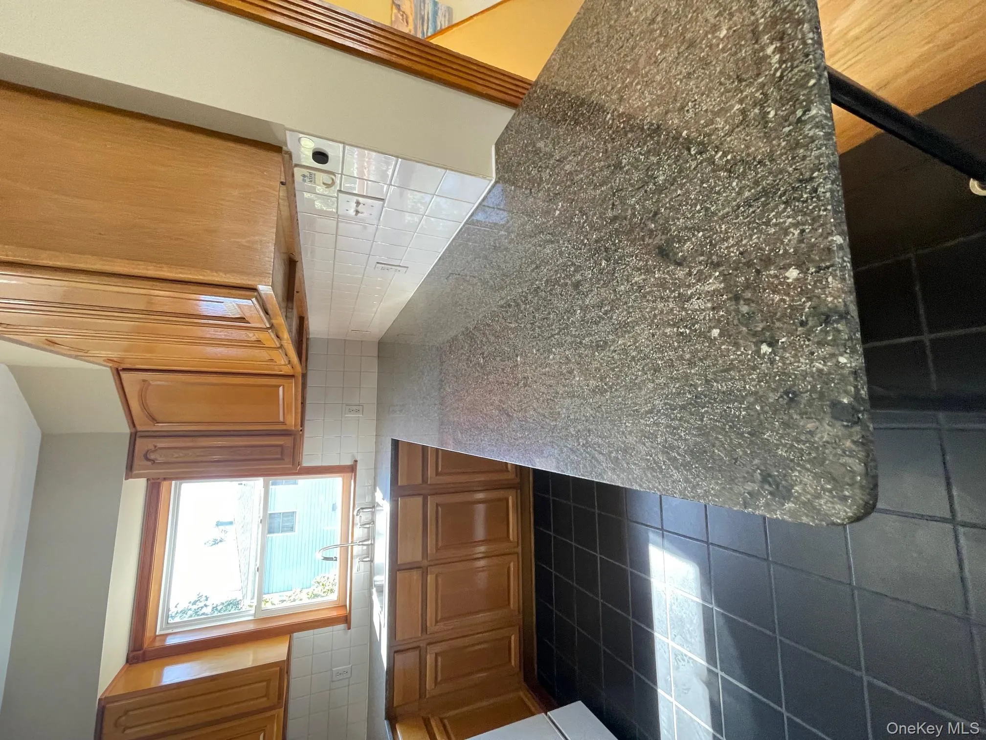 Kitchen featuring brown cabinets, backsplash, dark tile patterned flooring, and a peninsula Kitchen featuring brown cabinets, backsplash, dark tile patterned flooring, and a peninsula