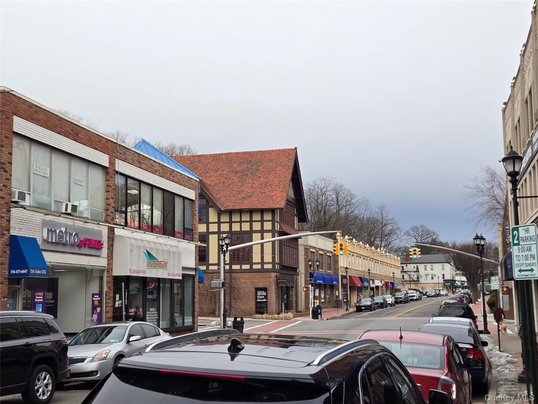 View of asphalt road with traffic lights, street lights, sidewalks, and curbs View of asphalt road with traffic lights, street lights, sidewalks, and curbs