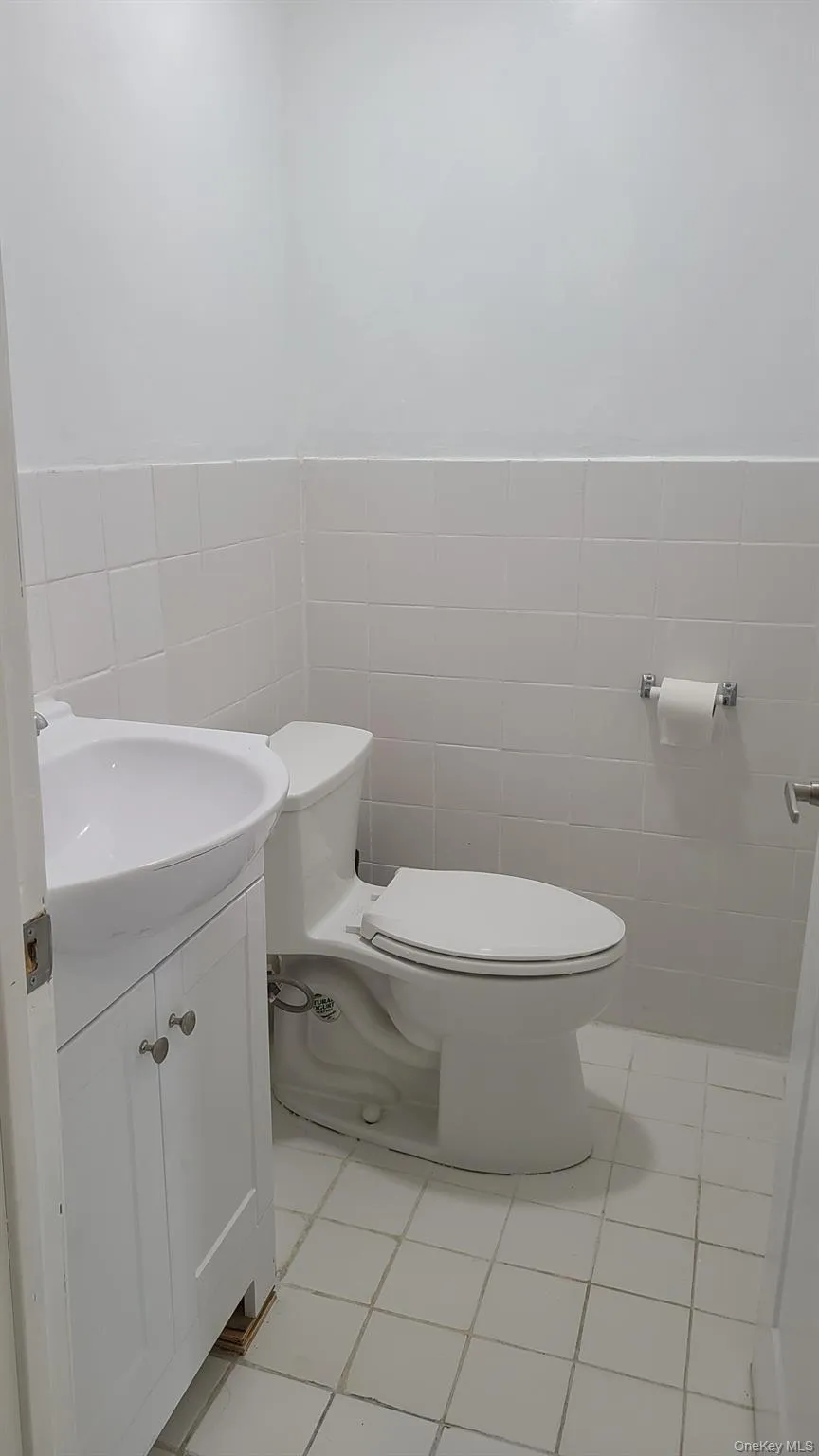 Bathroom with tile walls, vanity, light tile patterned floors, and wainscoting Bathroom with tile walls, vanity, light tile patterned floors, and wainscoting