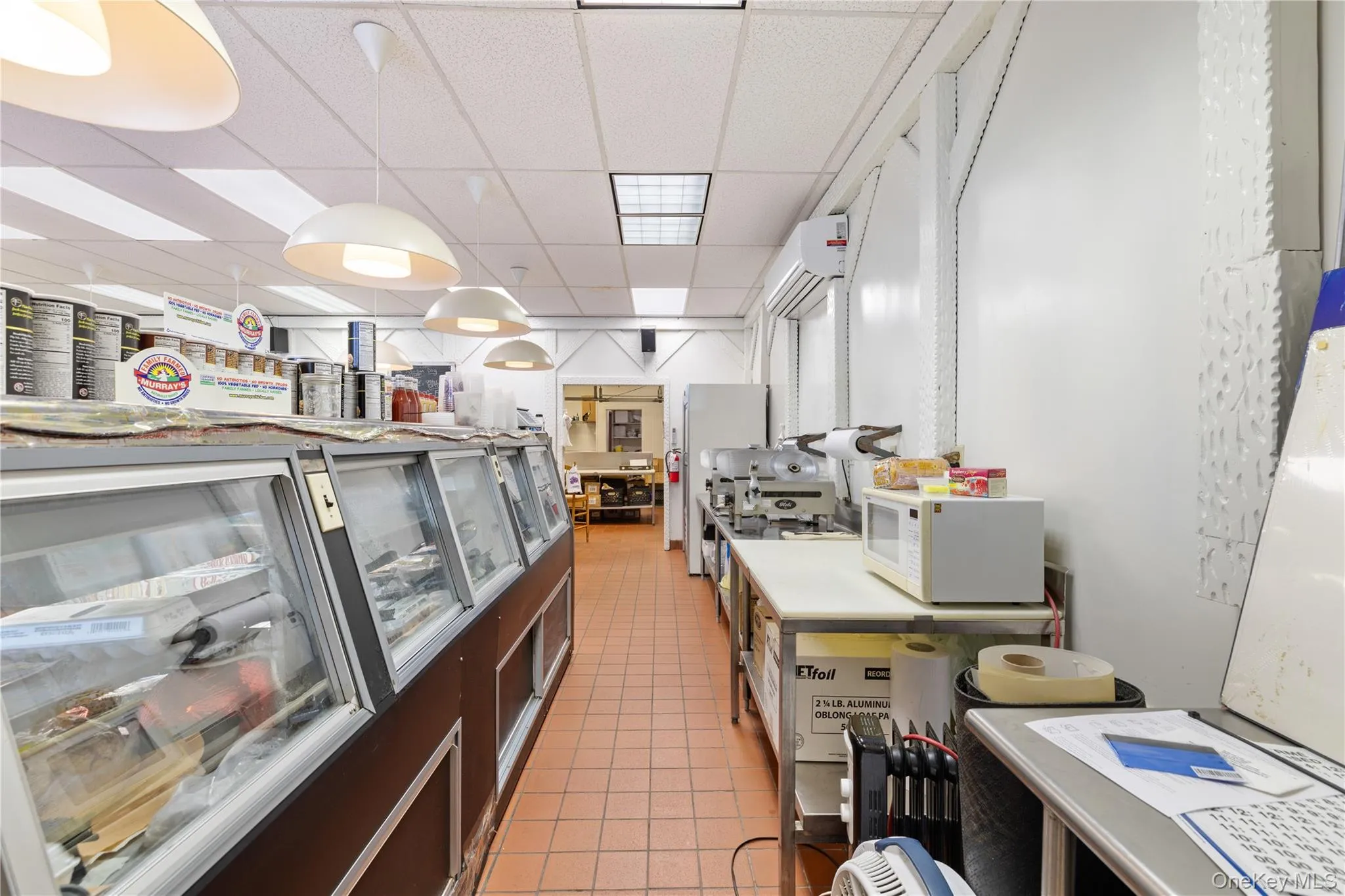 Kitchen with a drop ceiling, light tile patterned flooring, white microwave, light countertops, and range Kitchen with a drop ceiling, light tile patterned flooring, white microwave, light countertops, and range