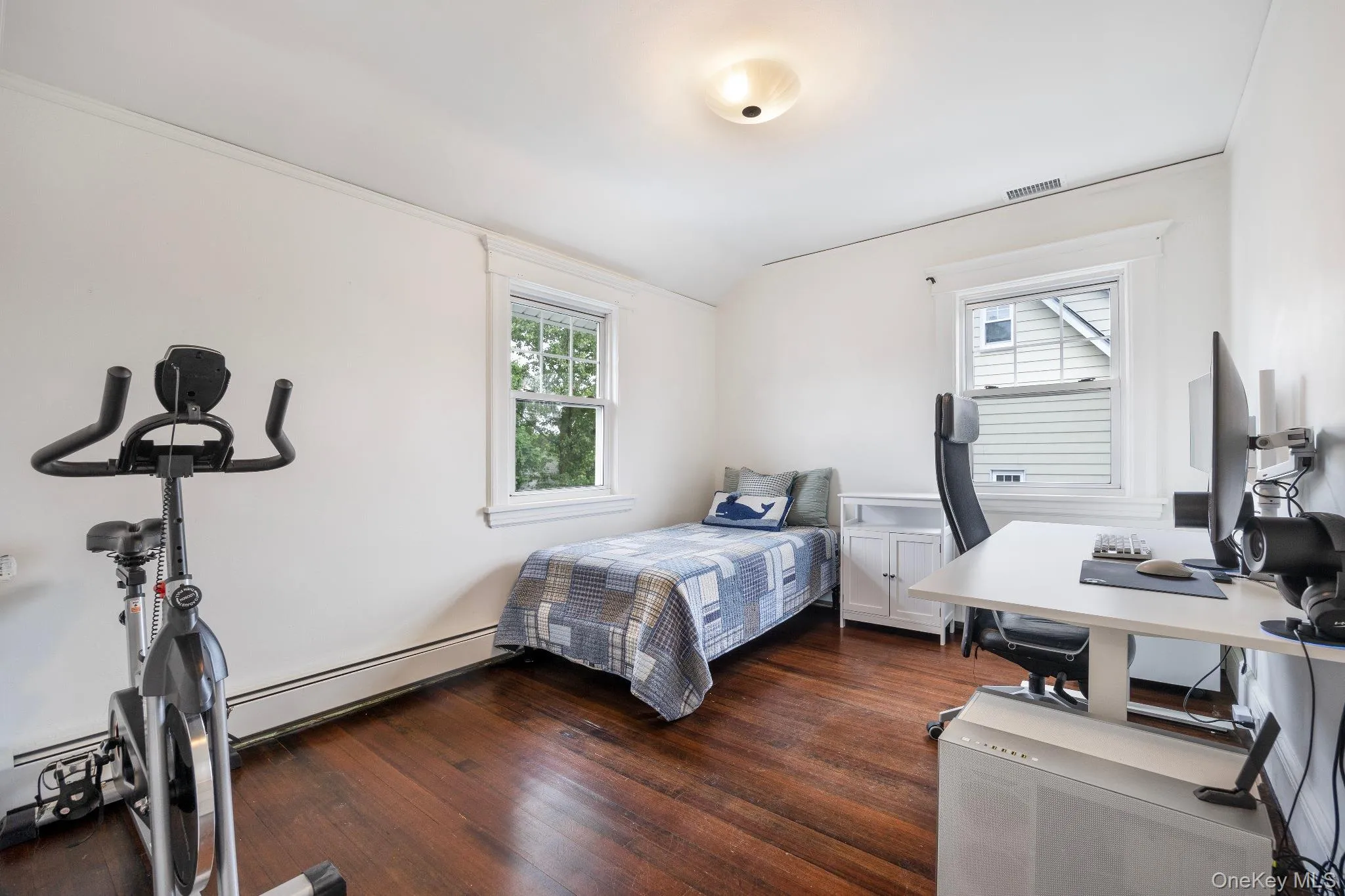 Bedroom featuring baseboard heating, dark wood-style flooring, lofted ceiling, and an office area Bedroom featuring baseboard heating, dark wood-style flooring, lofted ceiling, and an office area