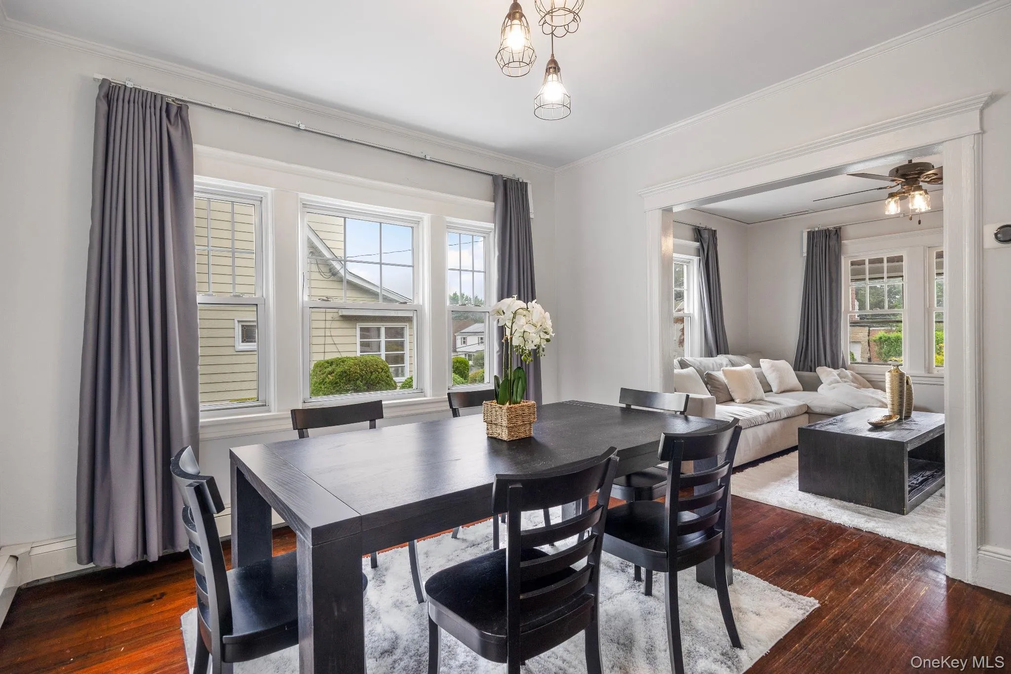 Dining area with dark wood-type flooring, ornamental molding, and a ceiling fan Dining area with dark wood-type flooring, ornamental molding, and a ceiling fan
