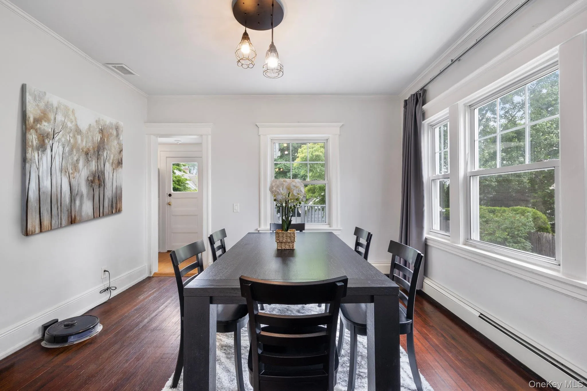 Dining space with baseboard heating, dark wood-style flooring, crown molding, and a chandelier Dining space with baseboard heating, dark wood-style flooring, crown molding, and a chandelier