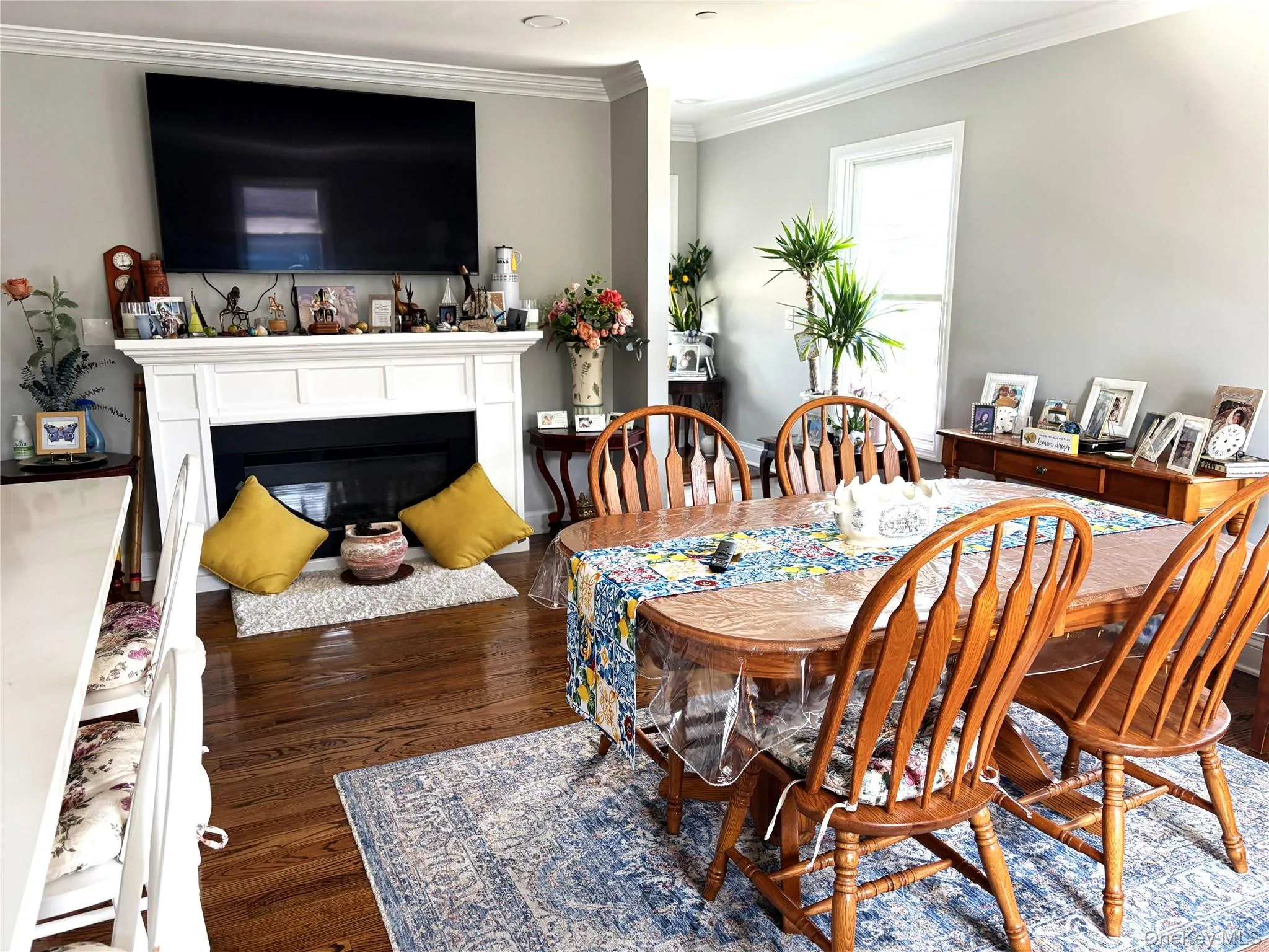 Dining area with crown molding, an electric fireplace, and dark hardwood floors Dining area with crown molding, an electric fireplace, and dark hardwood floors