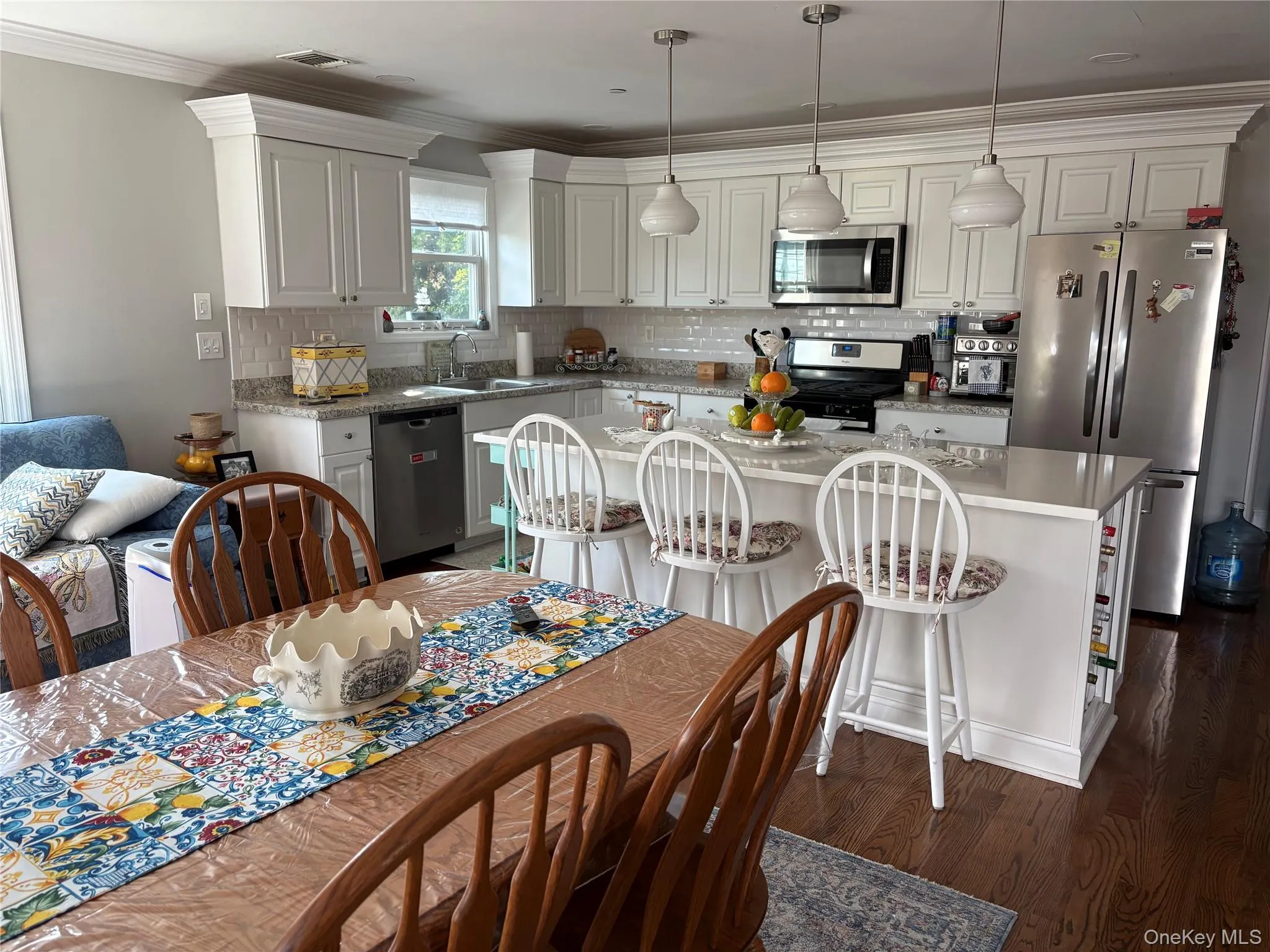 Kitchen with crown molding, stainless steel appliances, quartz countertops, a center island, and tasteful backsplash Kitchen with crown molding, stainless steel appliances, quartz countertops, a center island, and tasteful backsplash