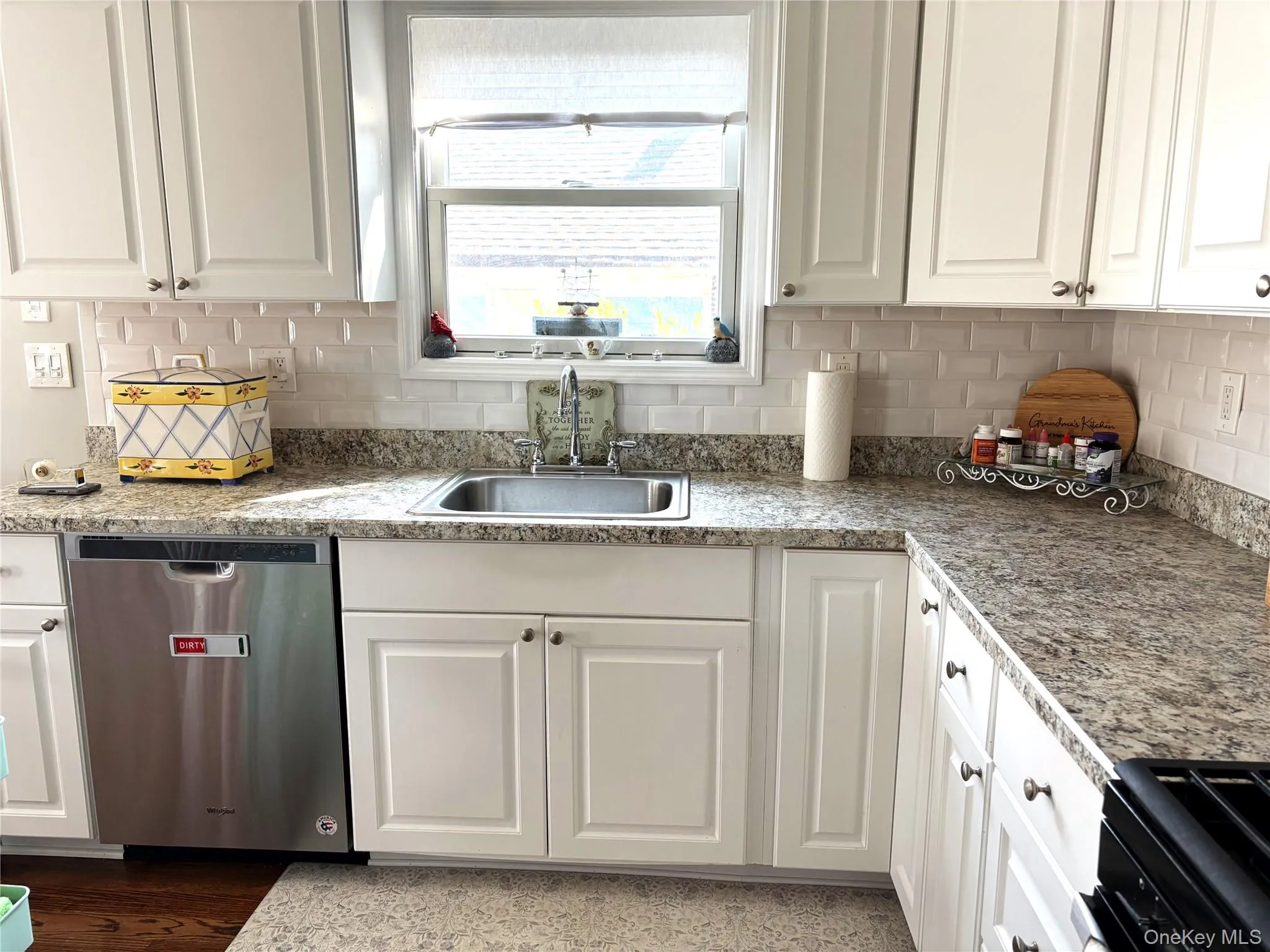 Kitchen with white cabinets, dishwasher, black gas range, and backsplash Kitchen with white cabinets, dishwasher, black gas range, and backsplash
