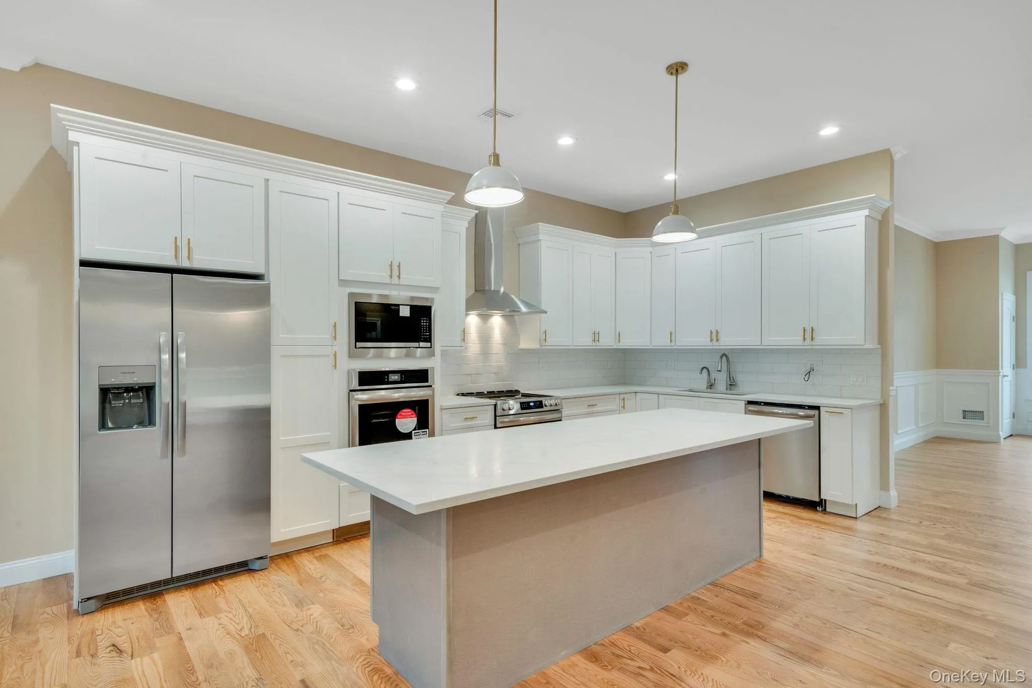 Kitchen featuring appliances with stainless steel finishes, crown molding, white cabinetry, pendant lighting, and a center island Kitchen featuring appliances with stainless steel finishes, crown molding, white cabinetry, pendant lighting, and a center island