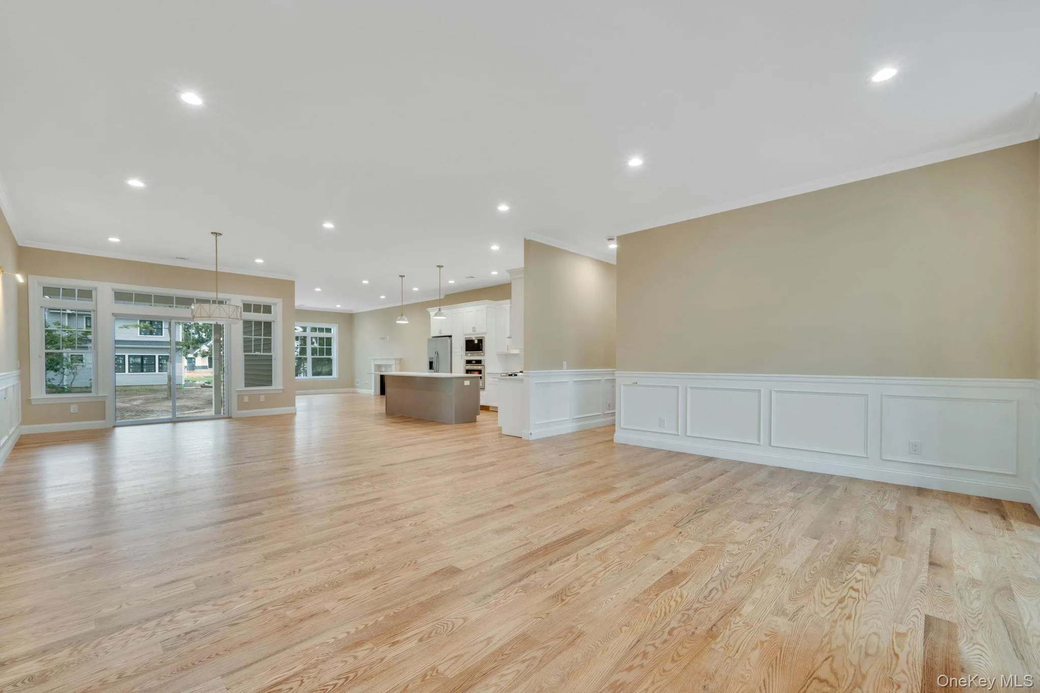 Unfurnished living room with a decorative wall, wainscoting, recessed lighting, and light wood-type flooring Unfurnished living room with a decorative wall, wainscoting, recessed lighting, and light wood-type flooring