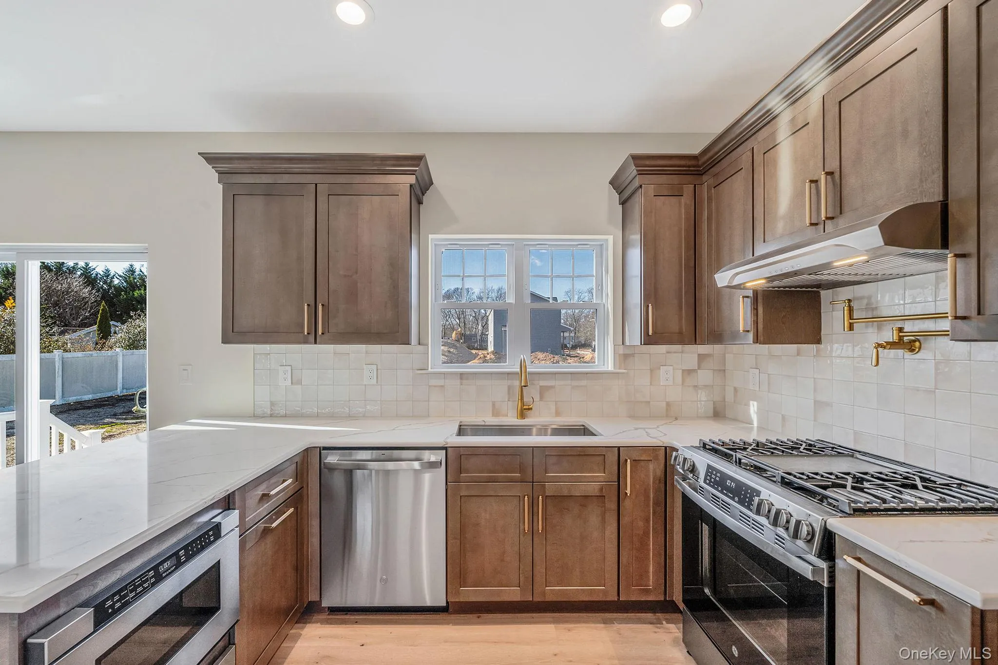 Kitchen with stainless steel appliances, under cabinet range hood, a peninsula, backsplash, and recessed lighting Kitchen with stainless steel appliances, under cabinet range hood, a peninsula, backsplash, and recessed lighting