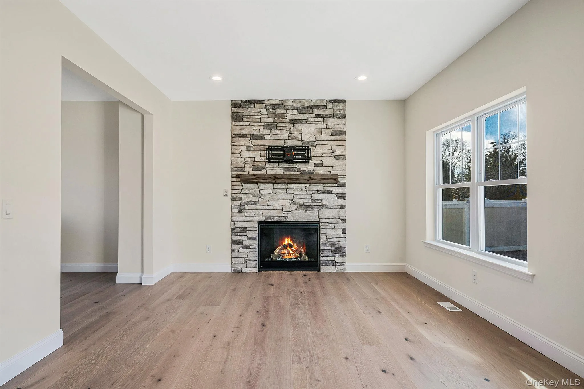Unfurnished living room featuring a stone fireplace, light wood-type flooring, and recessed lighting Unfurnished living room featuring a stone fireplace, light wood-type flooring, and recessed lighting
