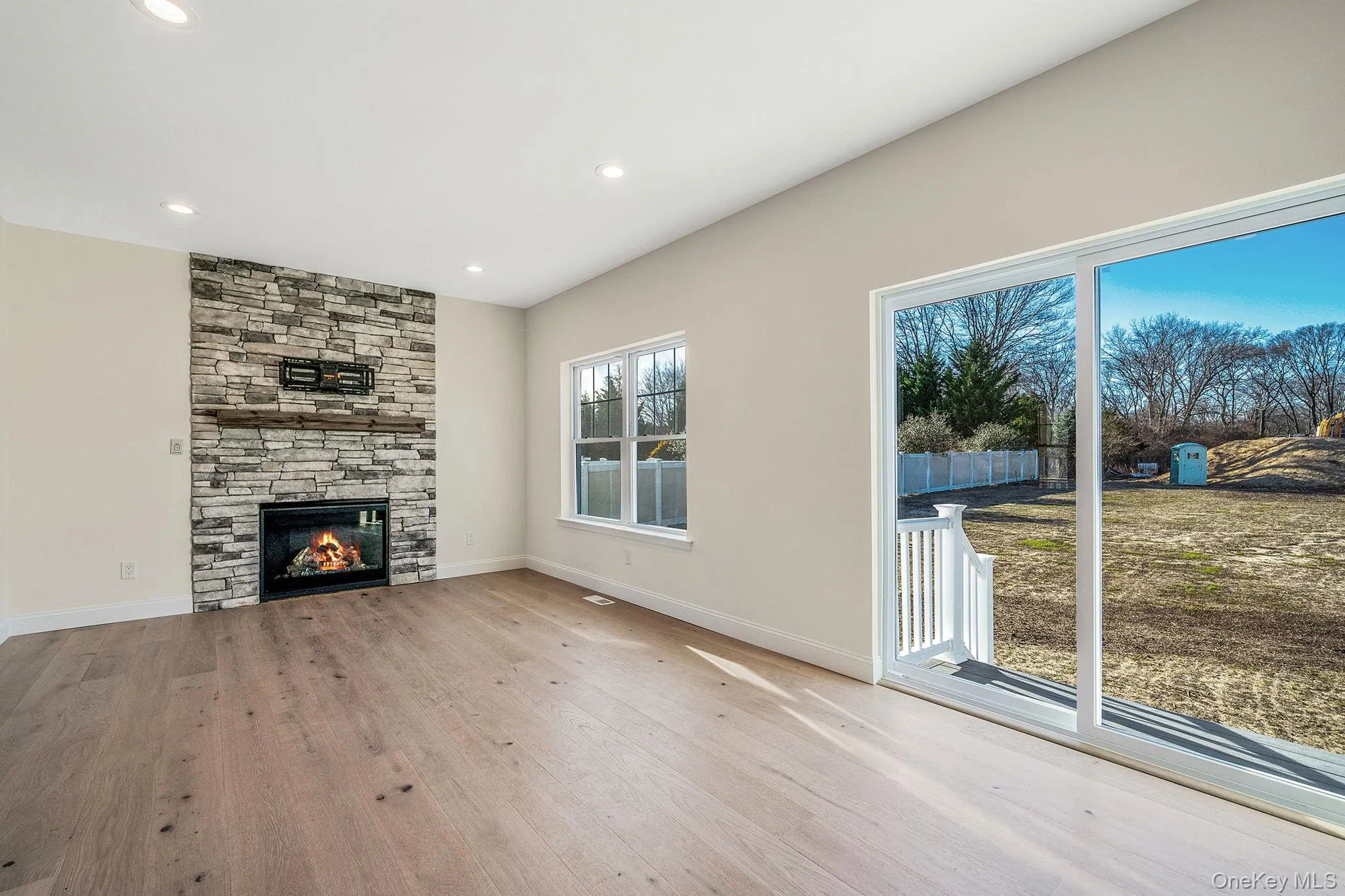 Unfurnished living room with light wood-type flooring, a fireplace, and recessed lighting Unfurnished living room with light wood-type flooring, a fireplace, and recessed lighting