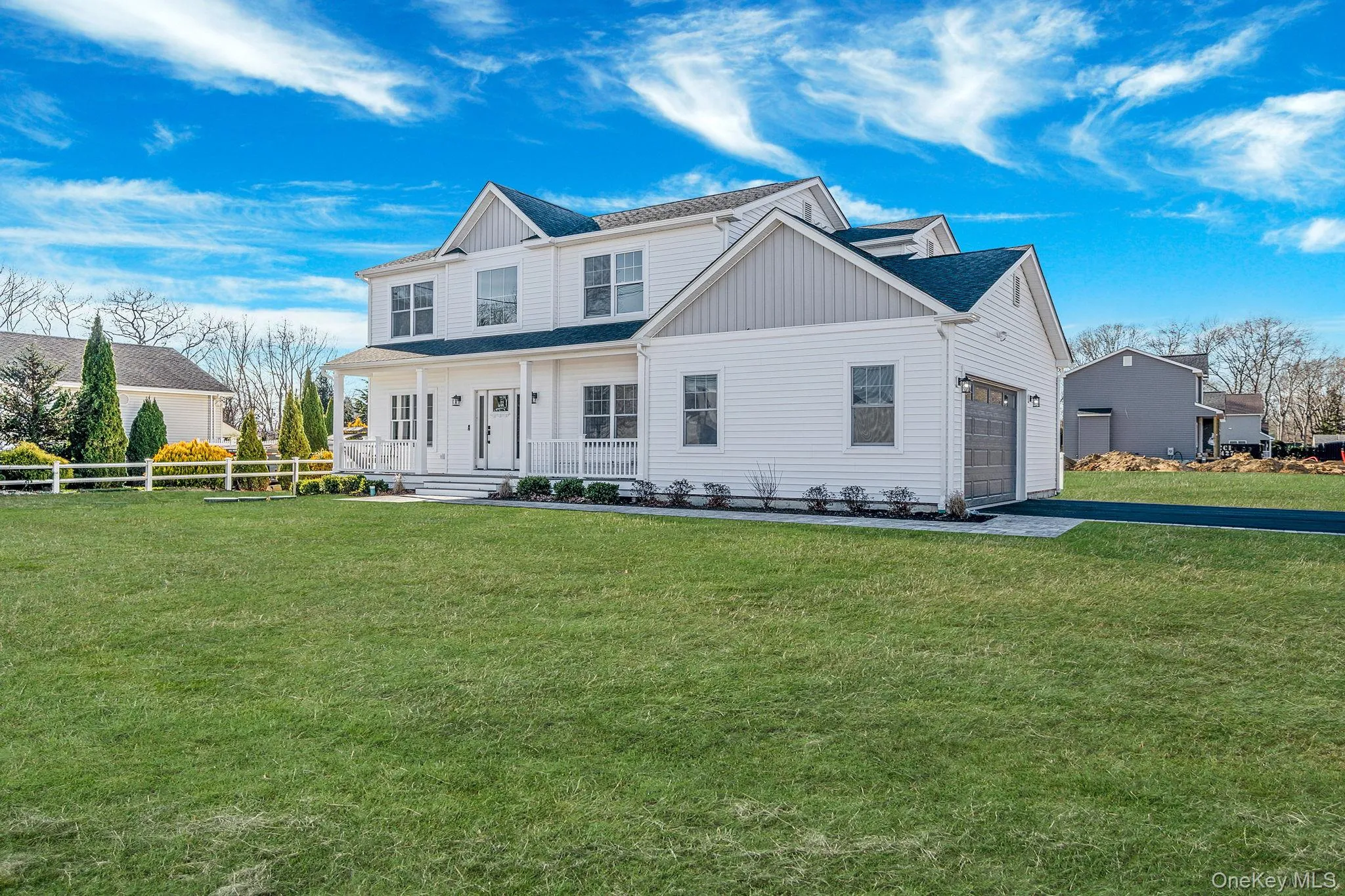Rear view of property with board and batten siding, covered porch, a shingled roof, driveway, and an attached garage Rear view of property with board and batten siding, covered porch, a shingled roof, driveway, and an attached garage