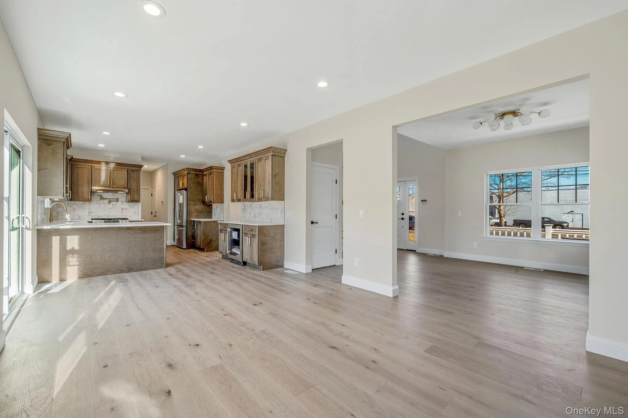 Unfurnished living room with light wood-type flooring, wine cooler, and recessed lighting Unfurnished living room with light wood-type flooring, wine cooler, and recessed lighting