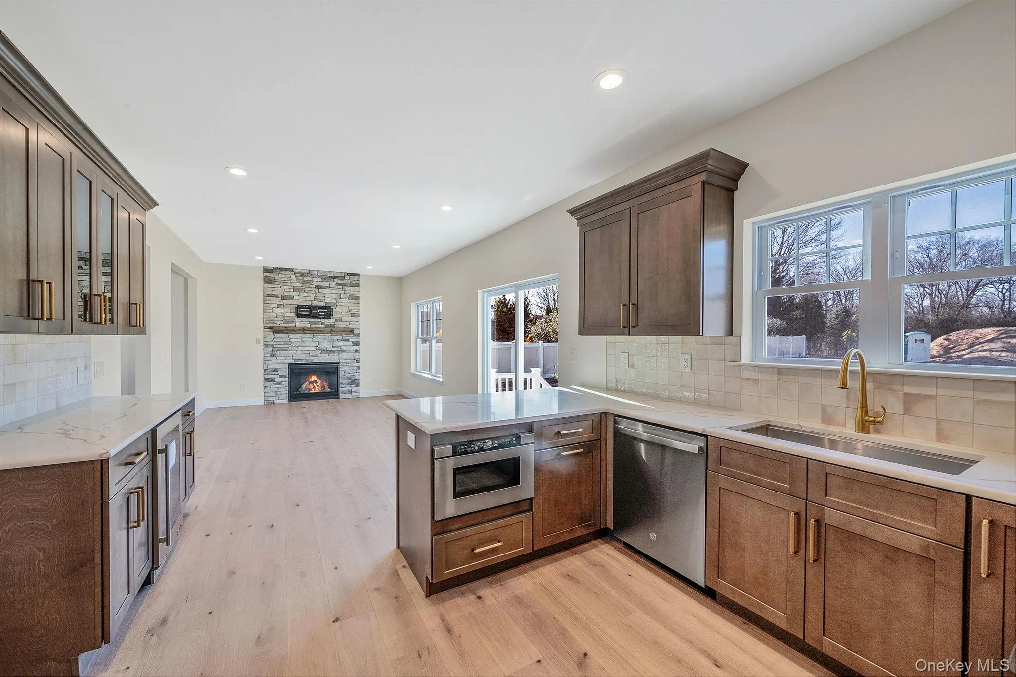 Kitchen with decorative backsplash, open floor plan, a peninsula, a fireplace, and recessed lighting Kitchen with decorative backsplash, open floor plan, a peninsula, a fireplace, and recessed lighting