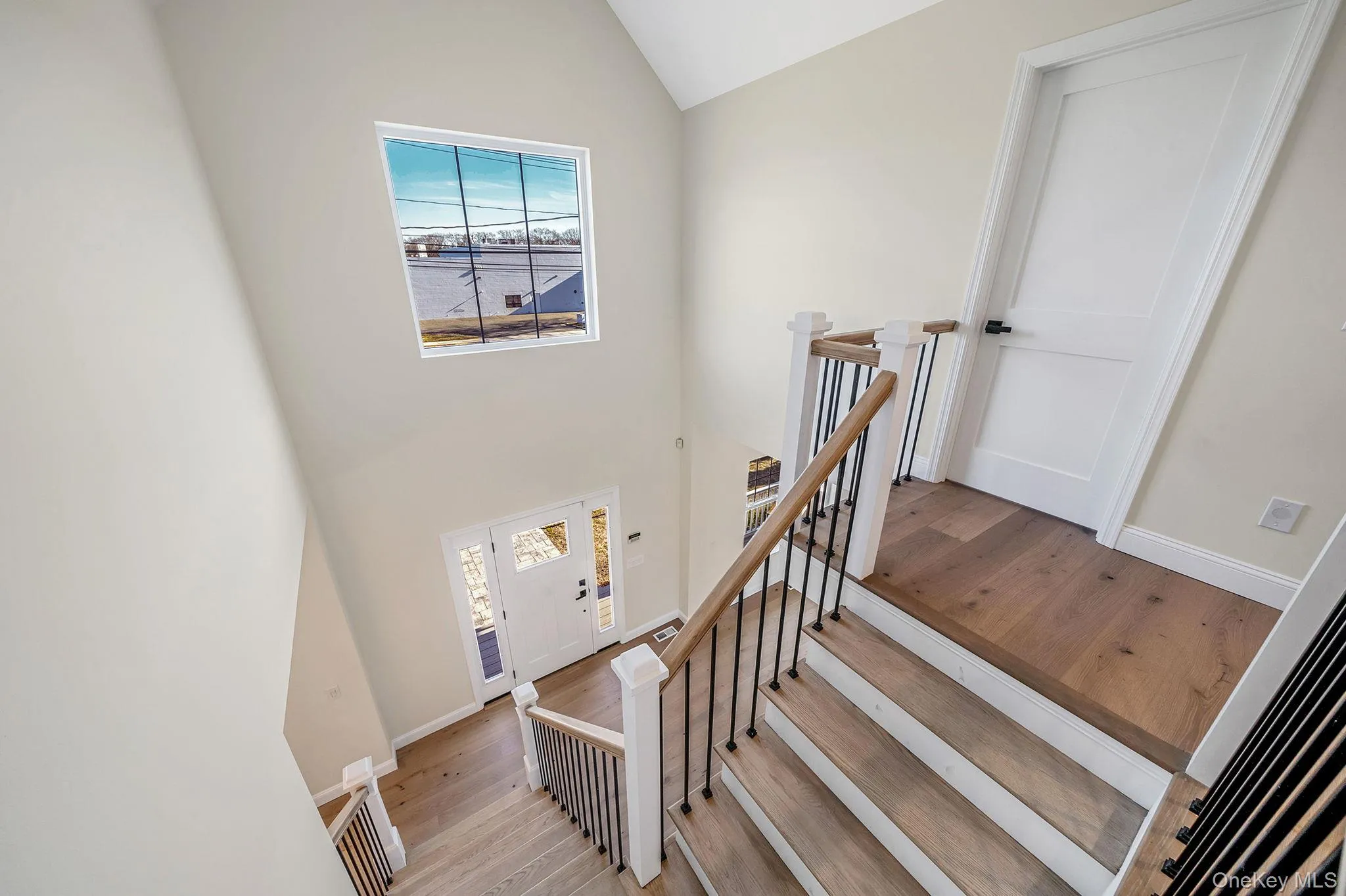 Stairway featuring wood-type flooring and a towering ceiling Stairway featuring wood-type flooring and a towering ceiling