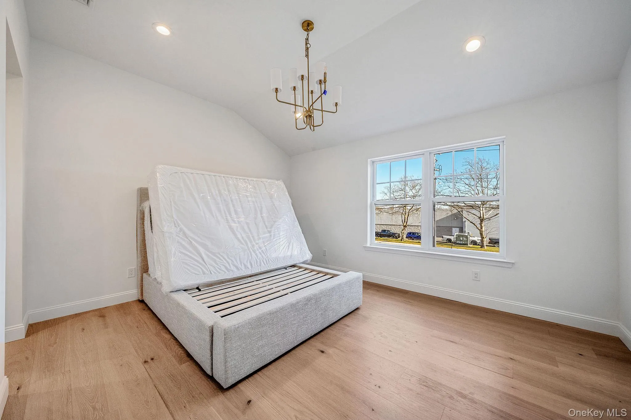 Bedroom with light wood-style flooring, vaulted ceiling, a chandelier, and recessed lighting Bedroom with light wood-style flooring, vaulted ceiling, a chandelier, and recessed lighting