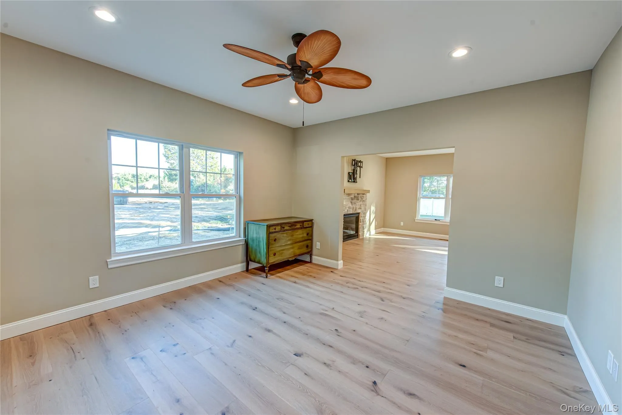 Empty room with light wood-style floors, ceiling fan, a glass covered fireplace, and recessed lighting Empty room with light wood-style floors, ceiling fan, a glass covered fireplace, and recessed lighting