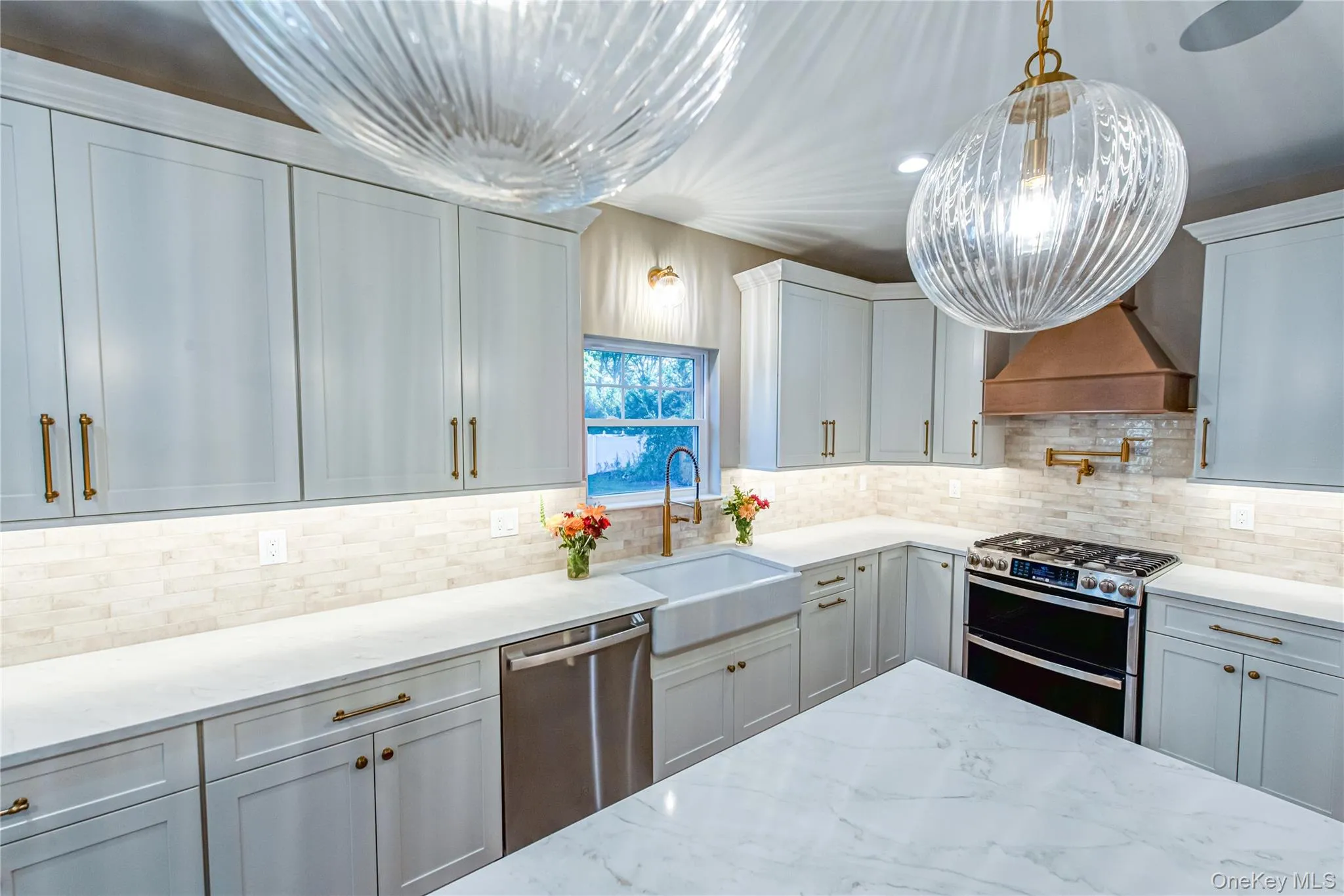 Kitchen with stainless steel appliances, light stone counters, recessed lighting, decorative backsplash, and decorative light fixtures Kitchen with stainless steel appliances, light stone counters, recessed lighting, decorative backsplash, and decorative light fixtures