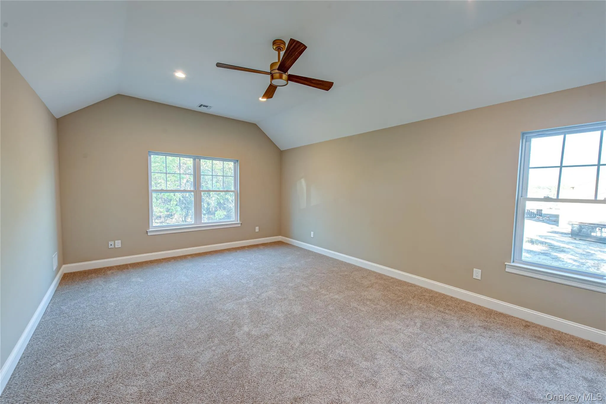 Empty room with lofted ceiling, light colored carpet, and ceiling fan Empty room with lofted ceiling, light colored carpet, and ceiling fan