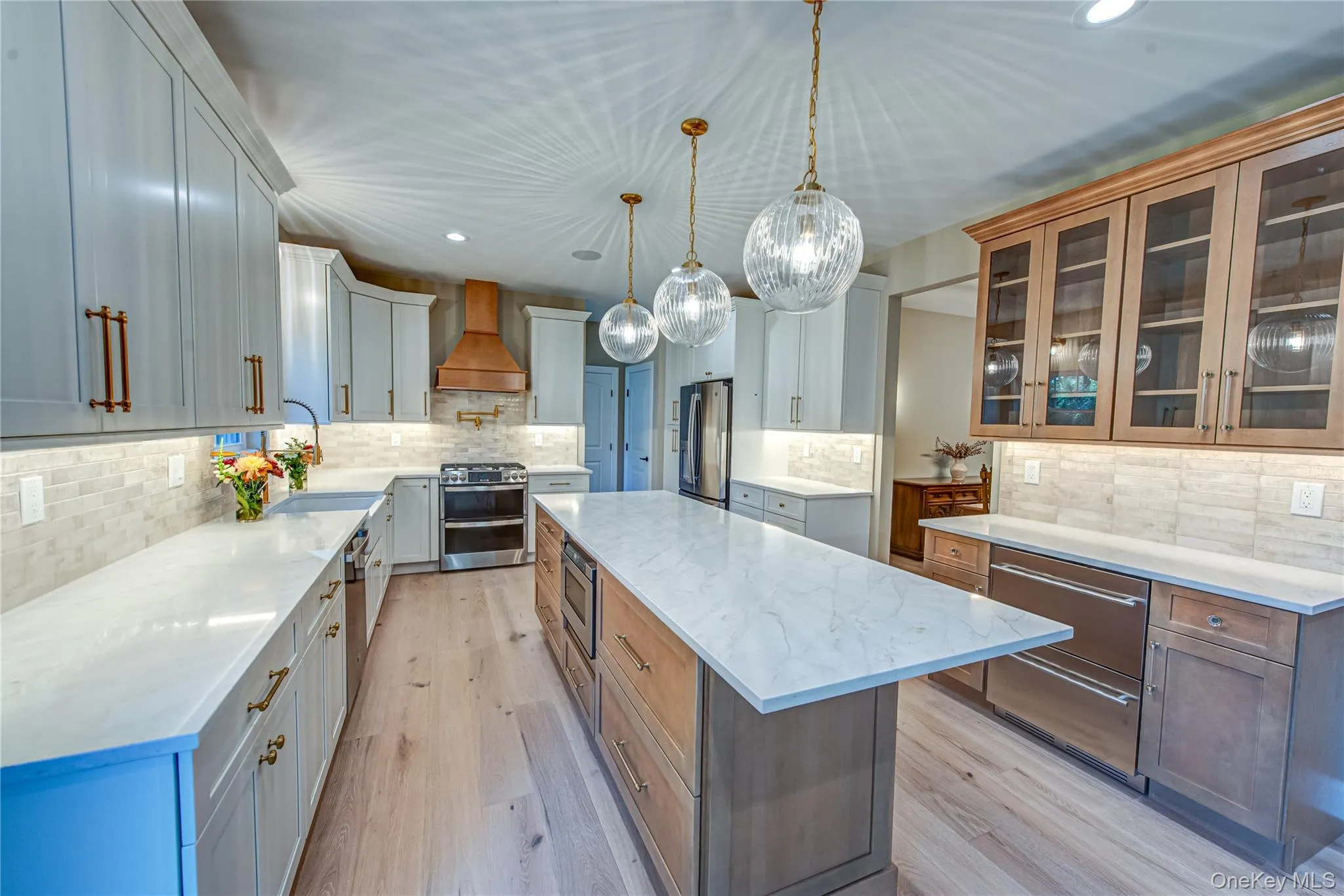 Kitchen with recessed lighting, glass insert cabinets, a kitchen island, light stone counters, and light wood-style floors Kitchen with recessed lighting, glass insert cabinets, a kitchen island, light stone counters, and light wood-style floors
