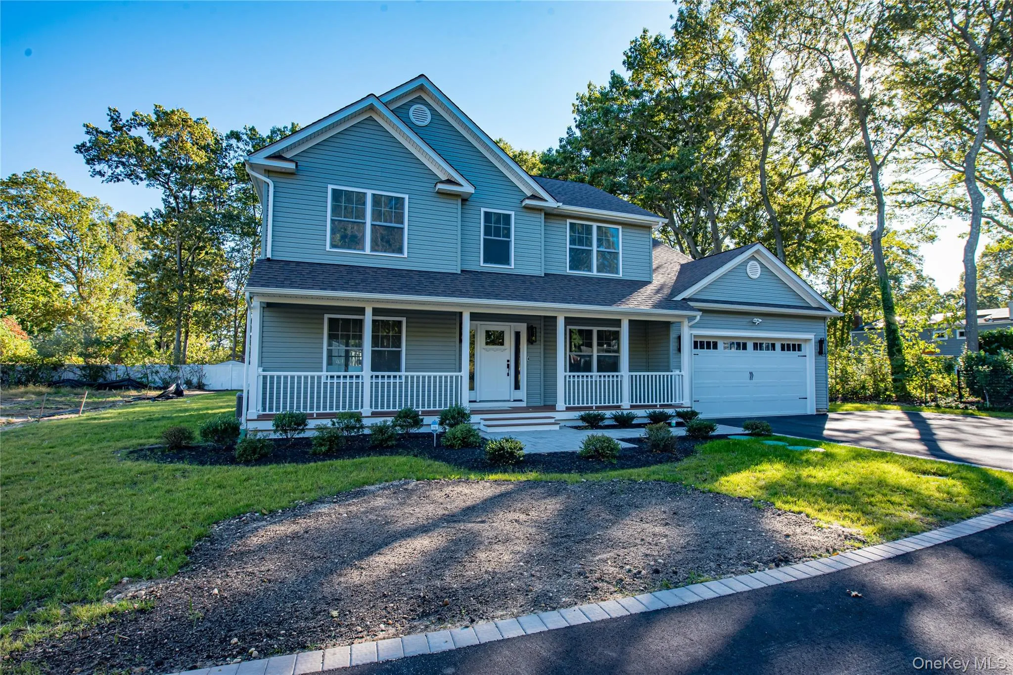 Traditional-style house with covered porch, asphalt driveway, roof with shingles, and a garage Traditional-style house with covered porch, asphalt driveway, roof with shingles, and a garage