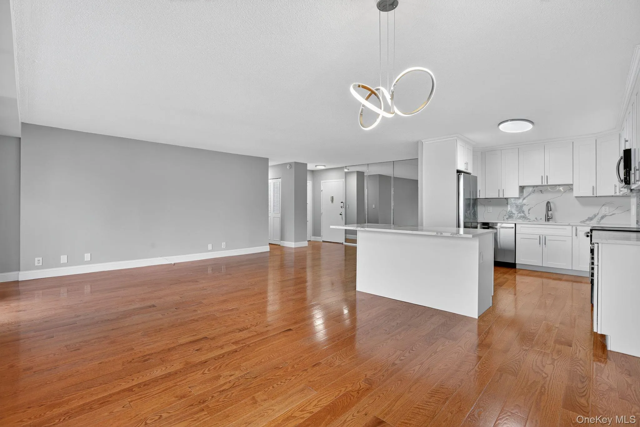 Kitchen with white cabinetry, light wood-style flooring, open floor plan, tasteful backsplash, and a center island Kitchen with white cabinetry, light wood-style flooring, open floor plan, tasteful backsplash, and a center island