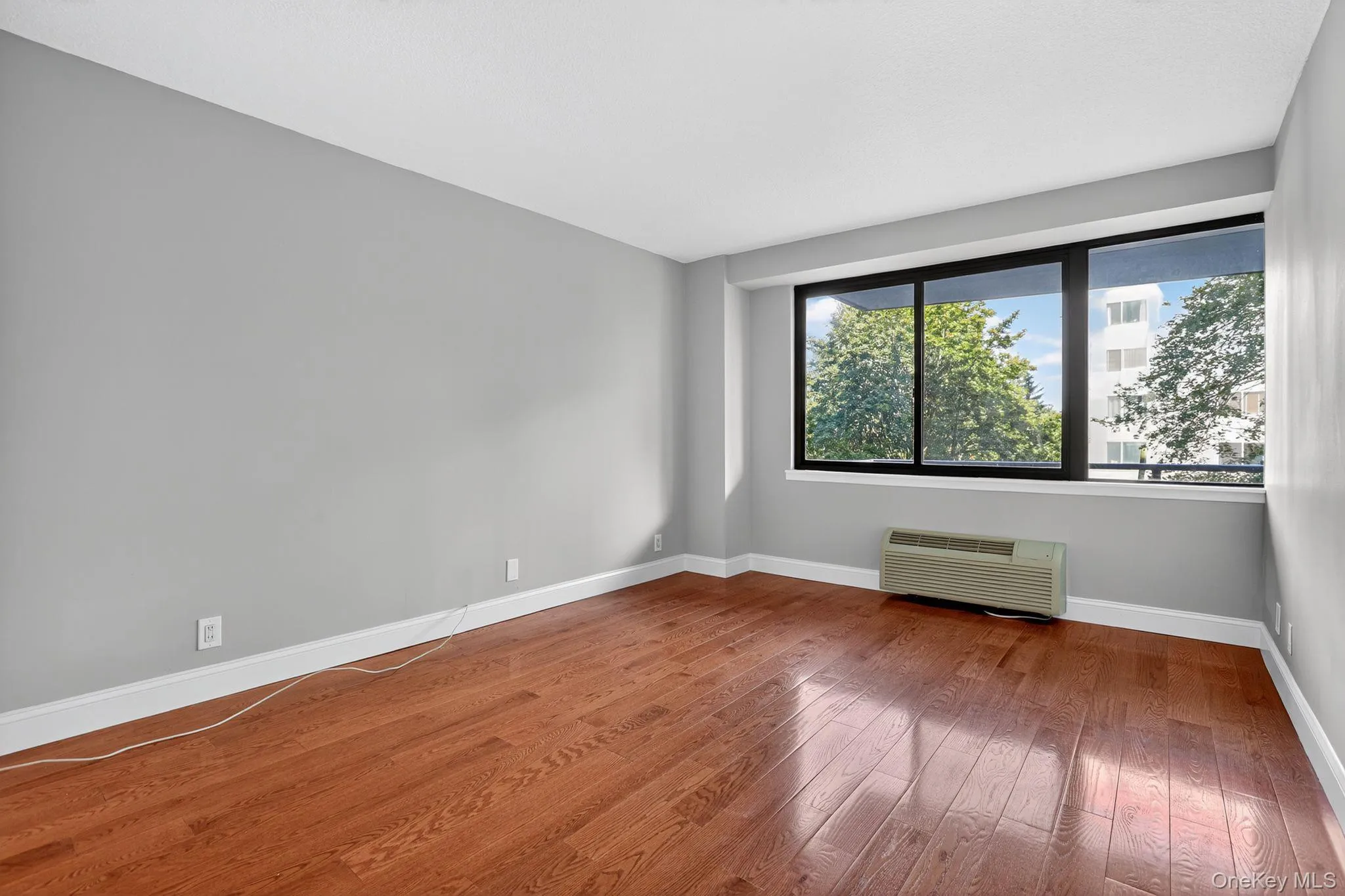 Empty room featuring hardwood / wood-style flooring and an AC wall unit Empty room featuring hardwood / wood-style flooring and an AC wall unit