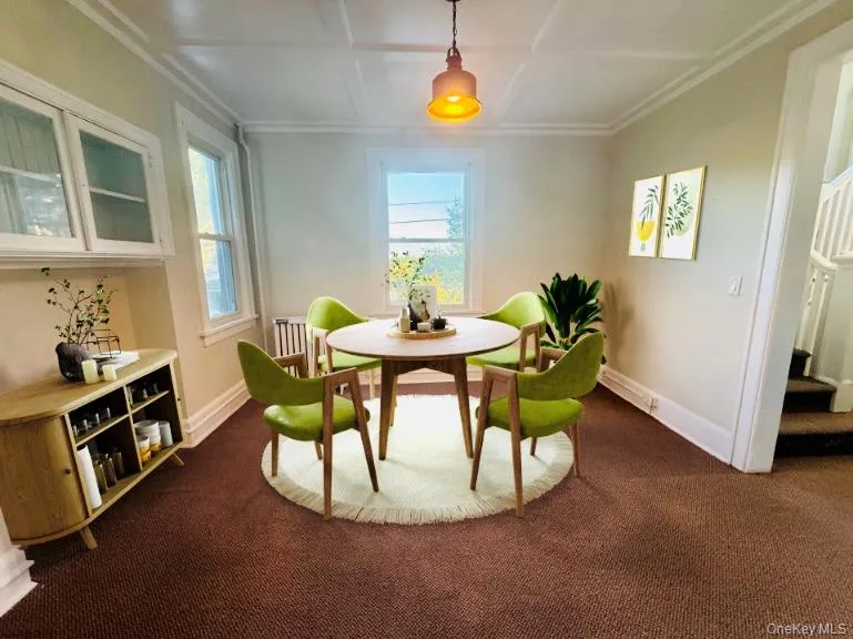 Dining area featuring plenty of natural light, coffered ceiling, dark colored carpet, stairs, and crown molding Dining area featuring plenty of natural light, coffered ceiling, dark colored carpet, stairs, and crown molding