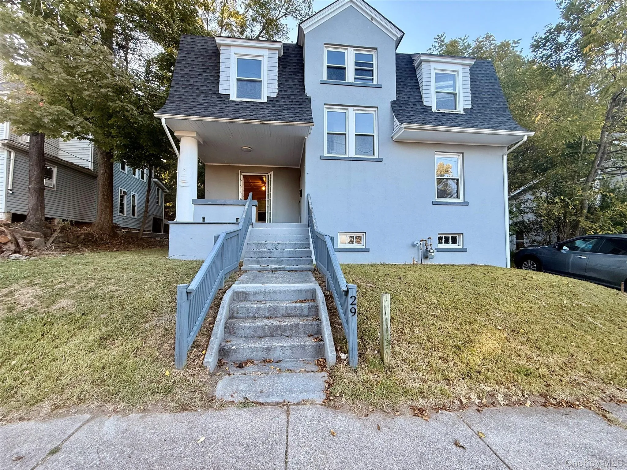 View of front facade with a shingled roof, a front lawn, covered porch, and stucco siding View of front facade with a shingled roof, a front lawn, covered porch, and stucco siding