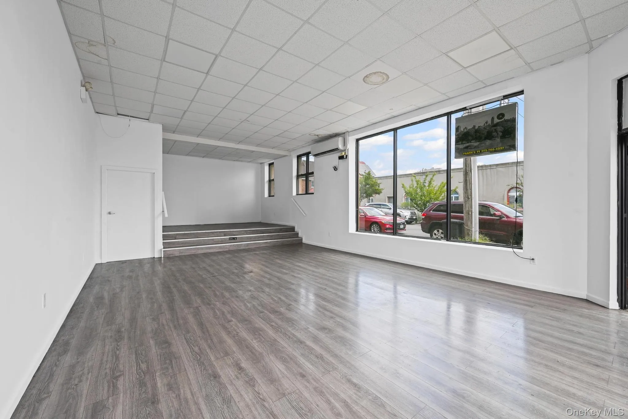 Spare room with a drop ceiling, wood finished floors, stairs, and a wall mounted air conditioner Spare room with a drop ceiling, wood finished floors, stairs, and a wall mounted air conditioner