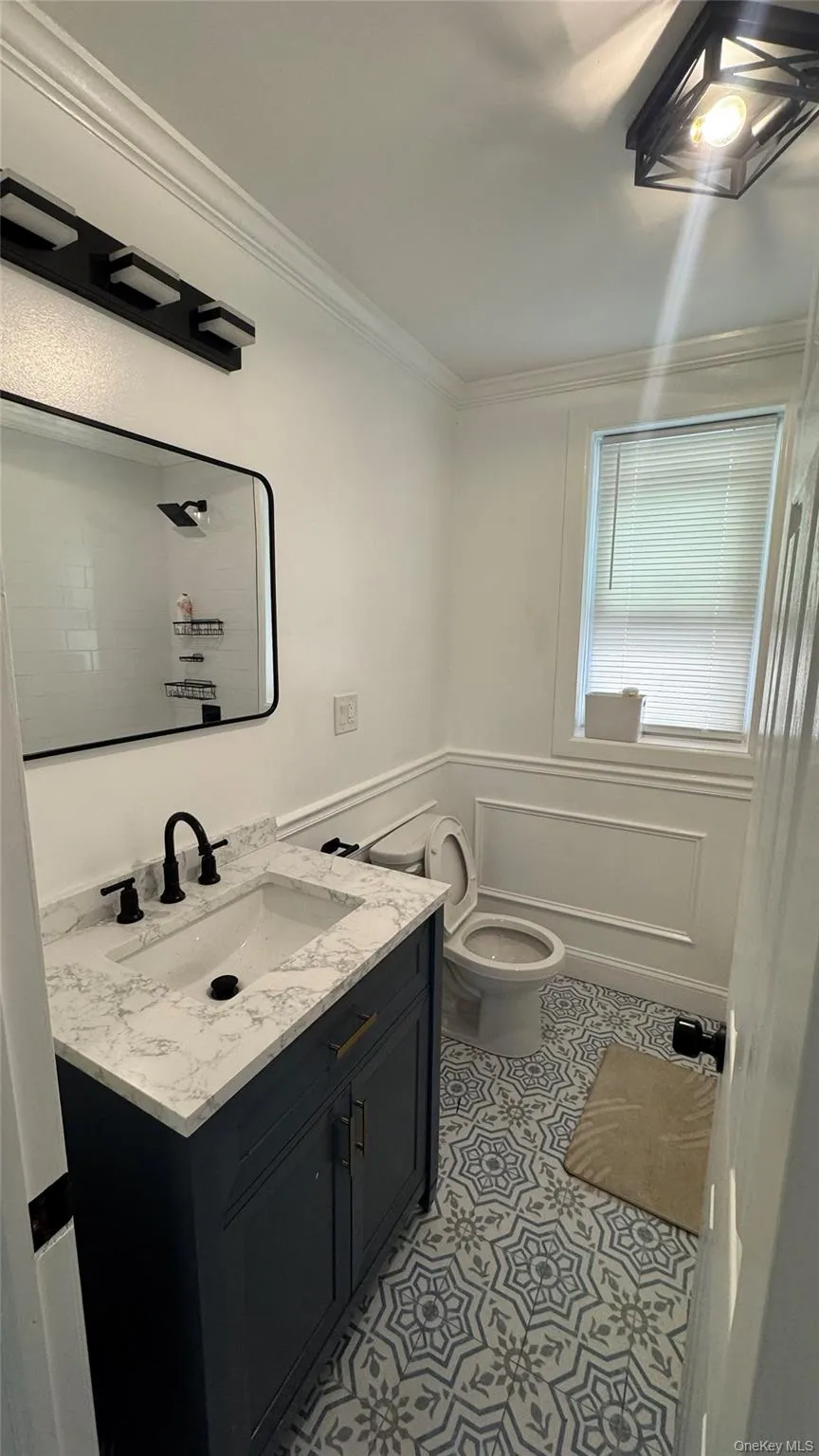 Bathroom featuring vanity, ornamental molding, and light tile patterned floors Bathroom featuring vanity, ornamental molding, and light tile patterned floors