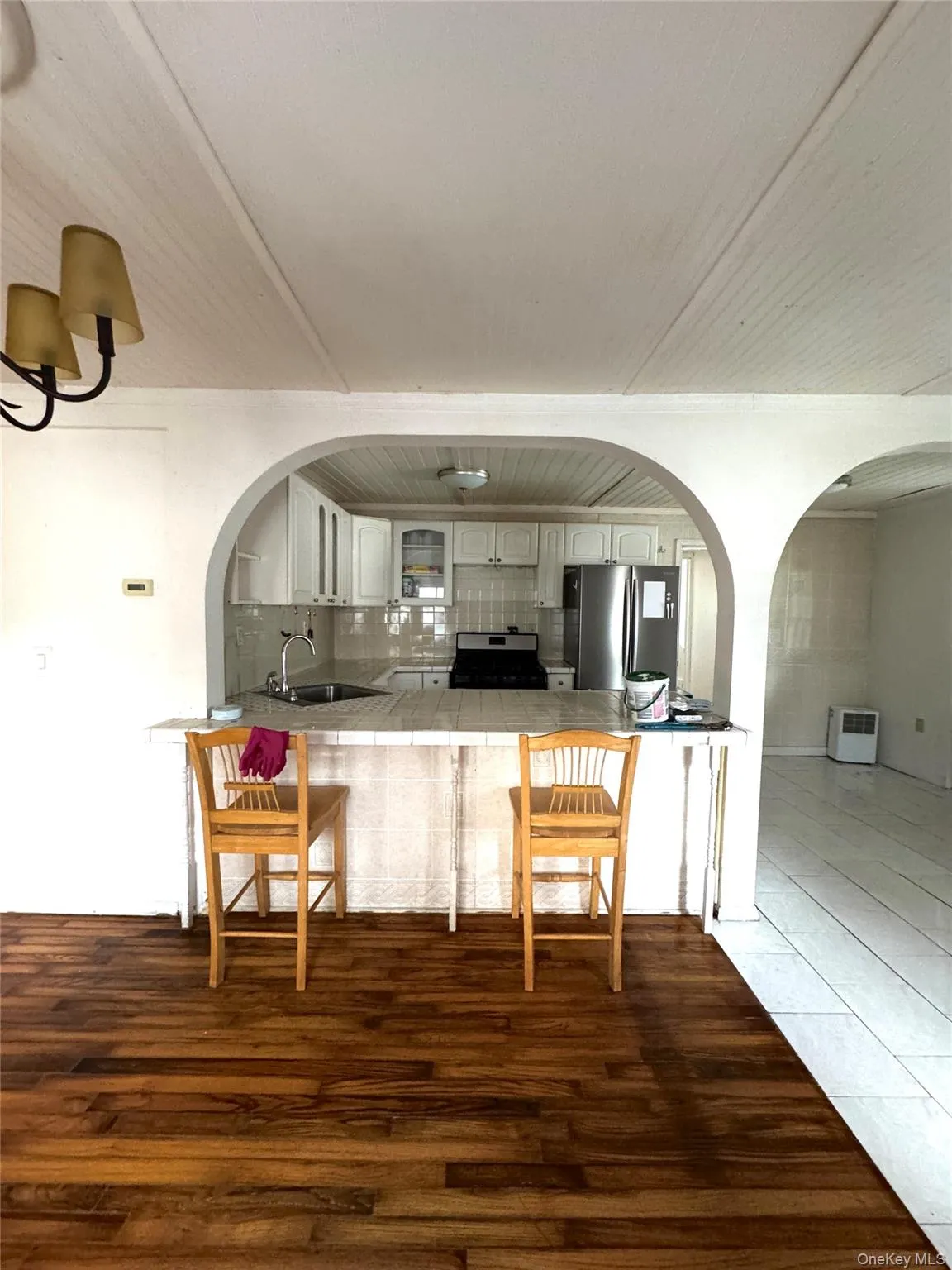 Kitchen featuring decorative backsplash, stainless steel appliances, glass insert cabinets, a peninsula, and dark wood finished floors Kitchen featuring decorative backsplash, stainless steel appliances, glass insert cabinets, a peninsula, and dark wood finished floors