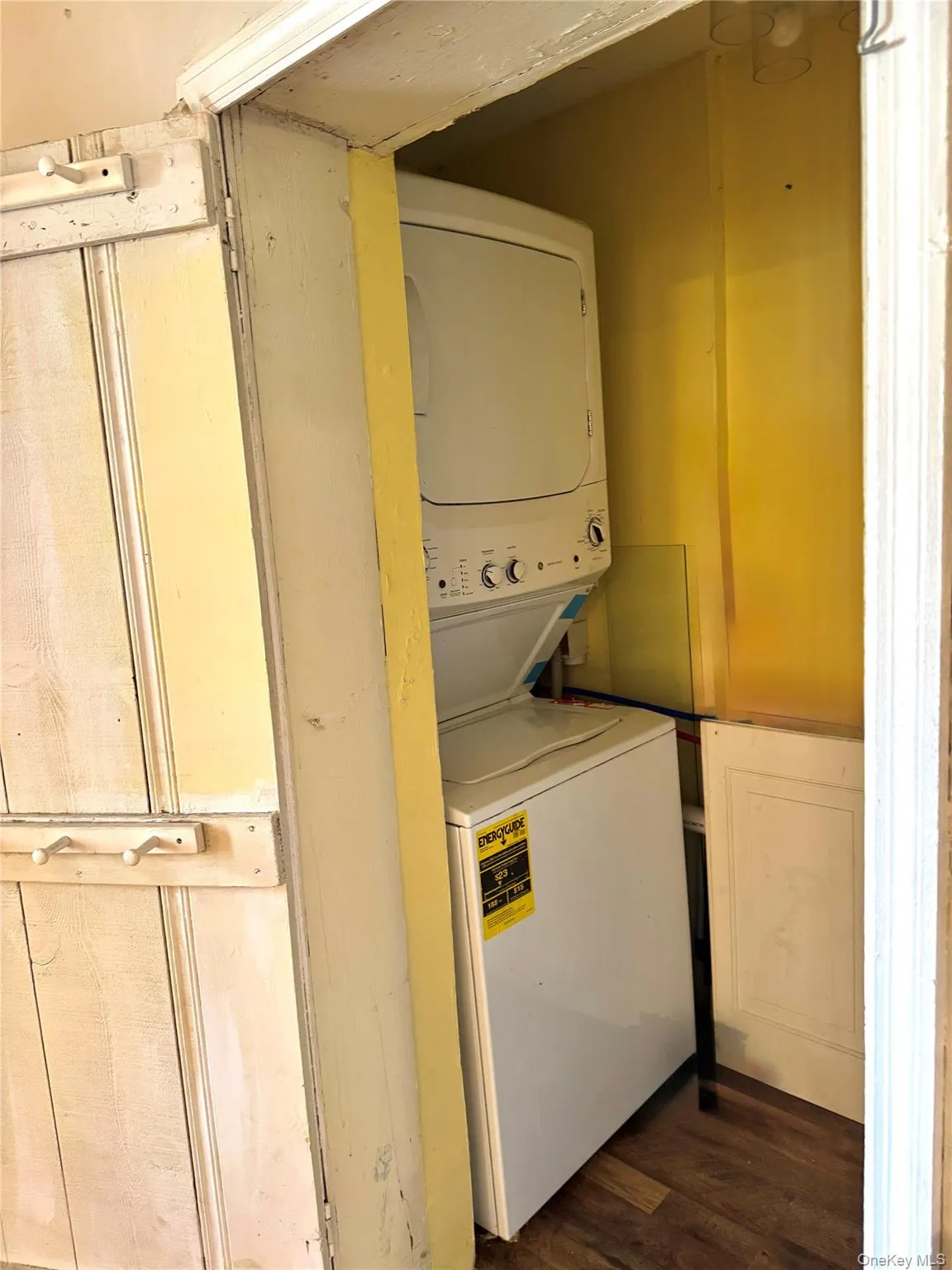 Laundry room featuring stacked washer / dryer, laundry area, and dark wood finished floors Laundry room featuring stacked washer / dryer, laundry area, and dark wood finished floors