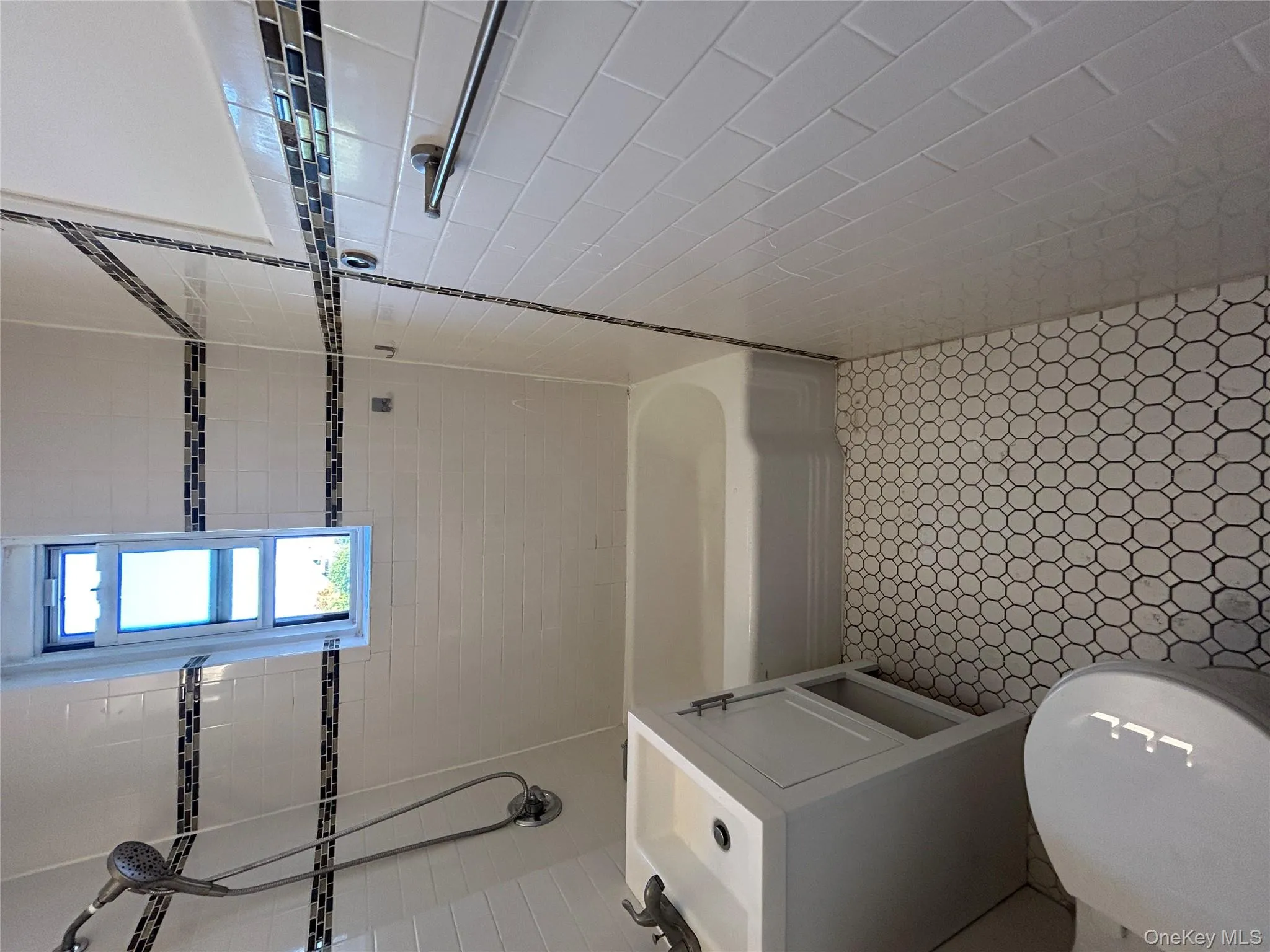 Full bathroom with vanity, tub / shower combination, light tile patterned floors, and tile walls Full bathroom with vanity, tub / shower combination, light tile patterned floors, and tile walls