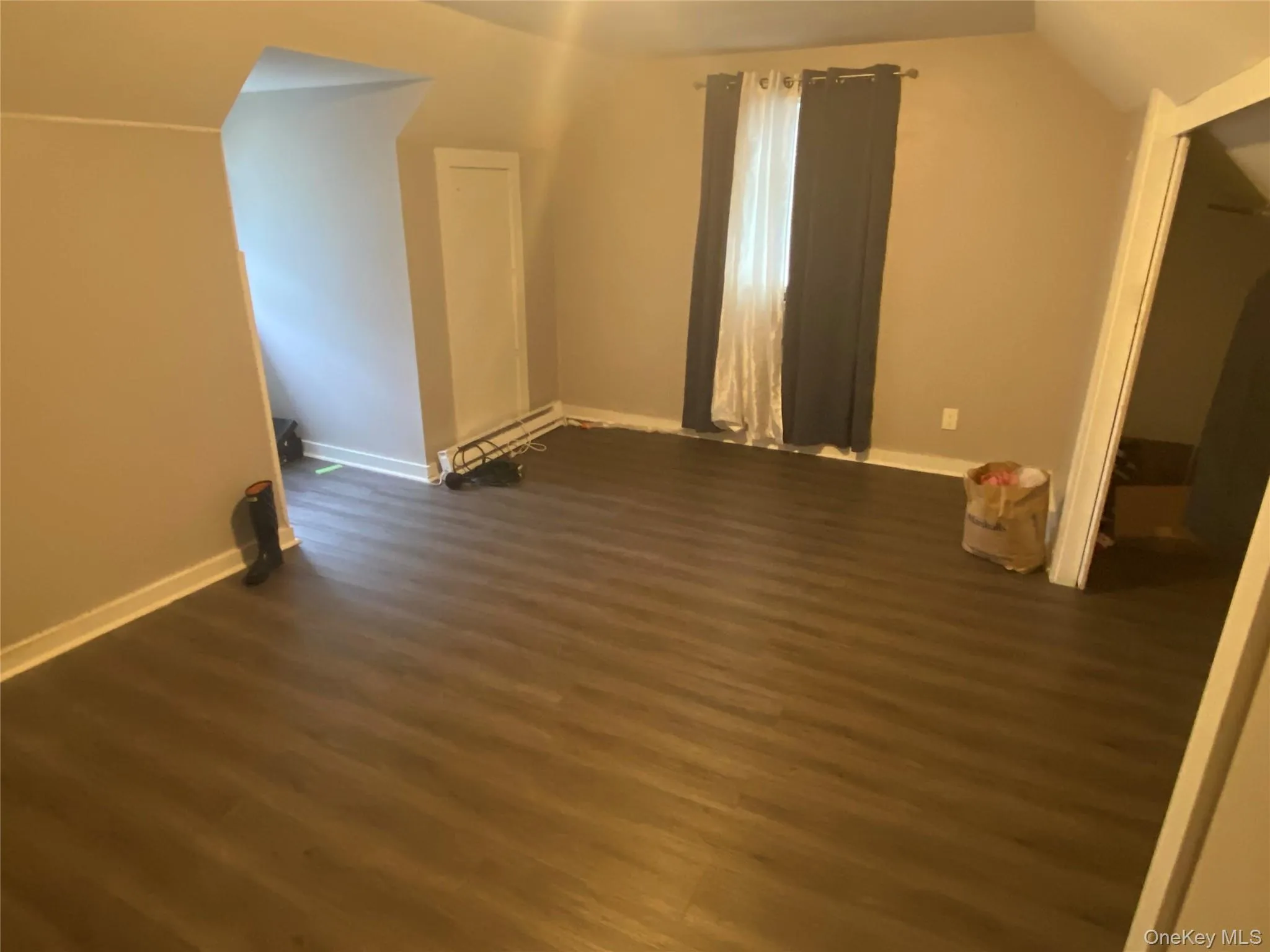 Bonus room with dark wood-style floors, lofted ceiling, and a baseboard heating unit Bonus room with dark wood-style floors, lofted ceiling, and a baseboard heating unit
