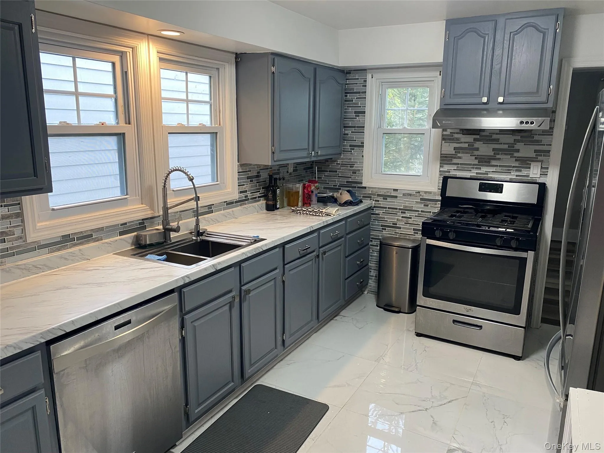 Kitchen featuring decorative backsplash and gray cabinetry Kitchen featuring decorative backsplash and gray cabinetry